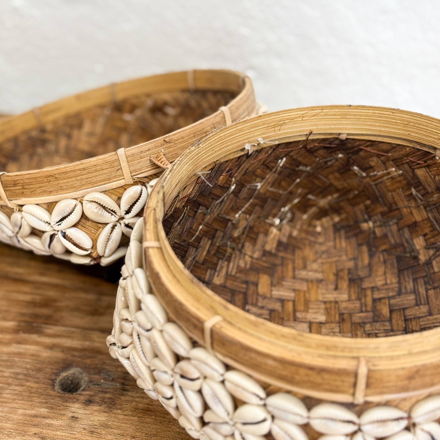 Woven basket with shell decorations on a wooden surface