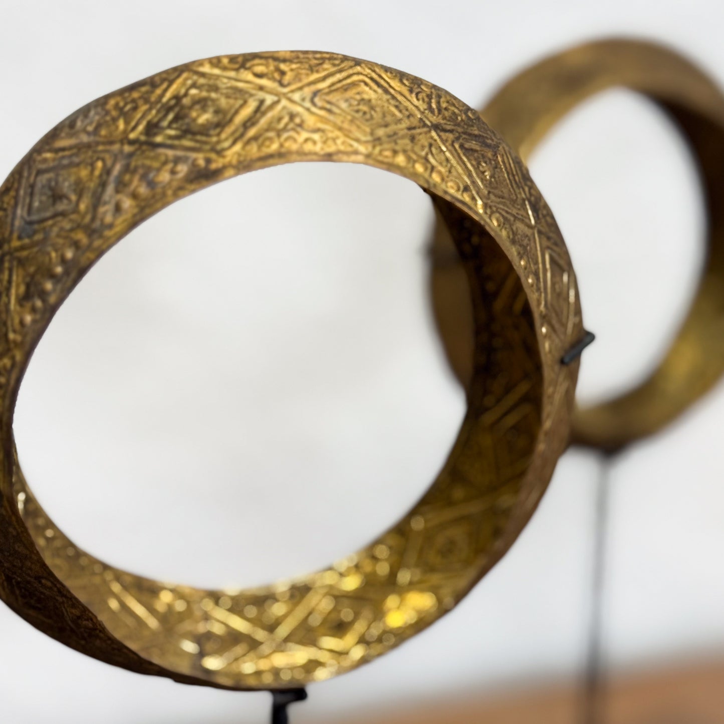 Decorative gold bangle with intricate patterns on a white background