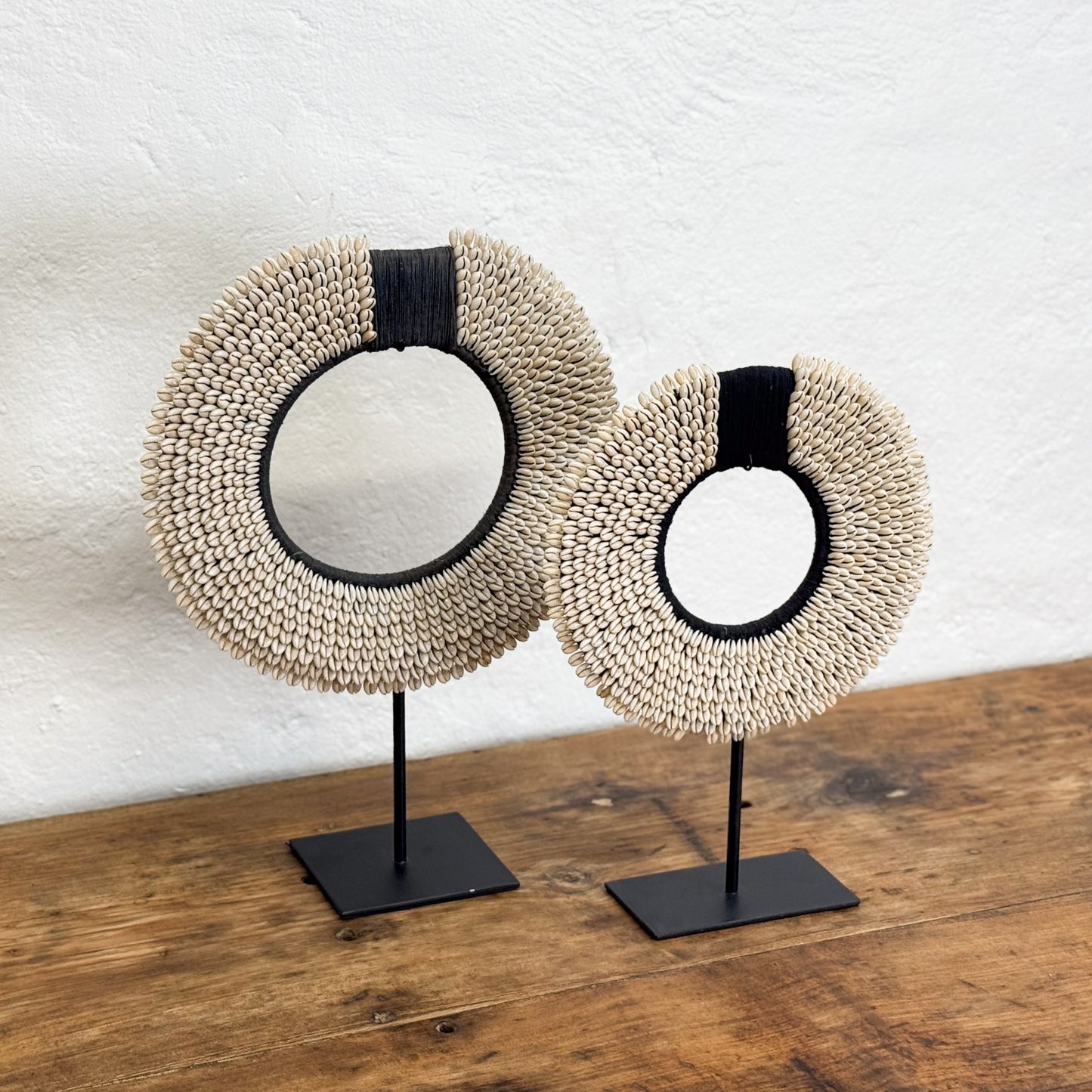 Two round woven mirrors on stands against a white wall.