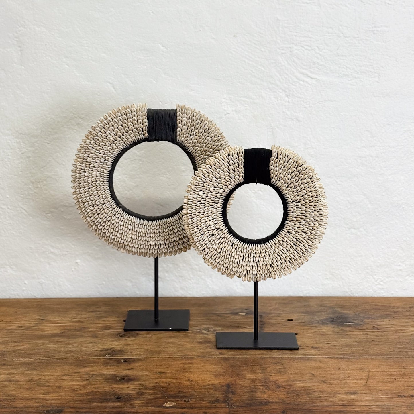 Two round woven mirrors on stands against a white wall.