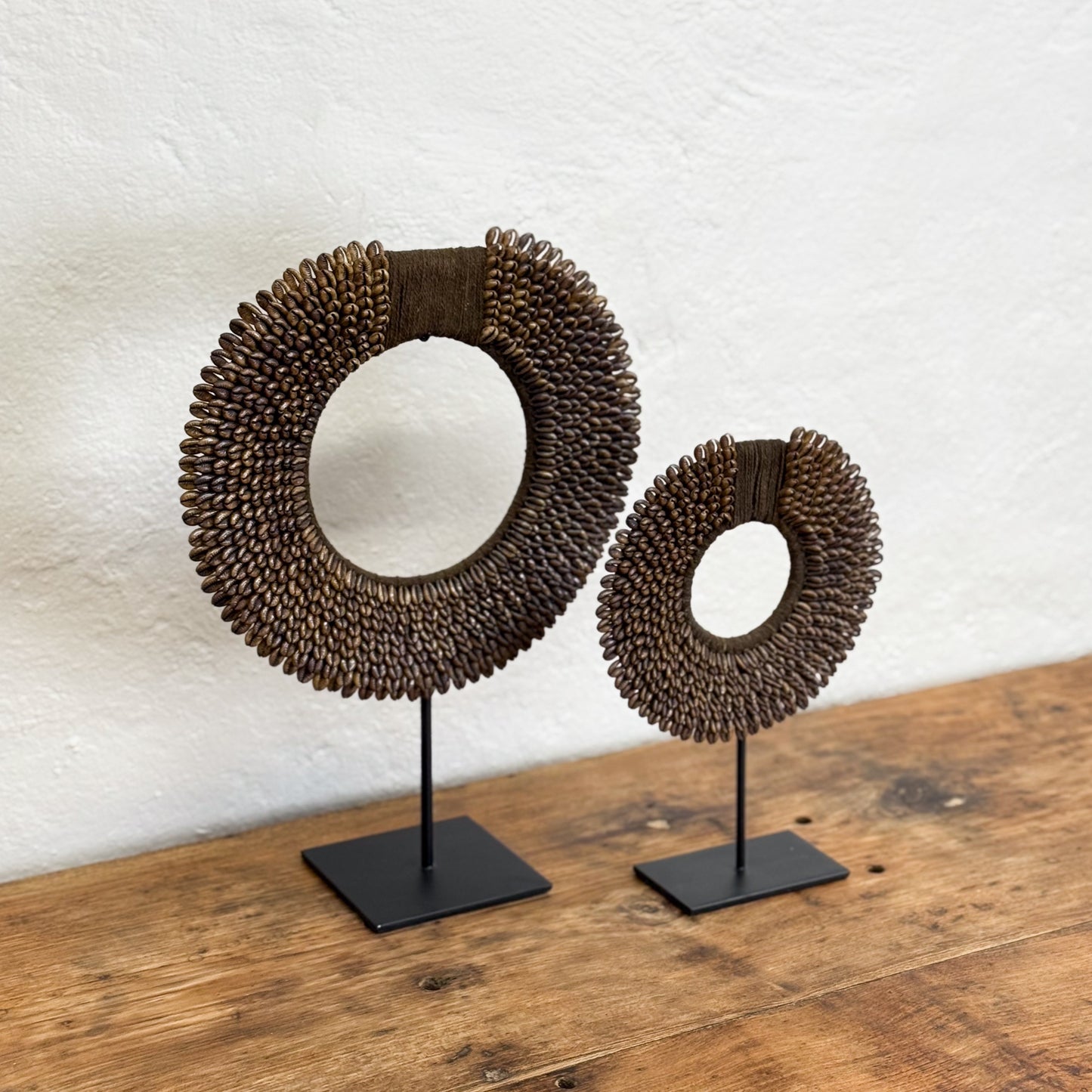 Two decorative circular objects on stands against a white wall.