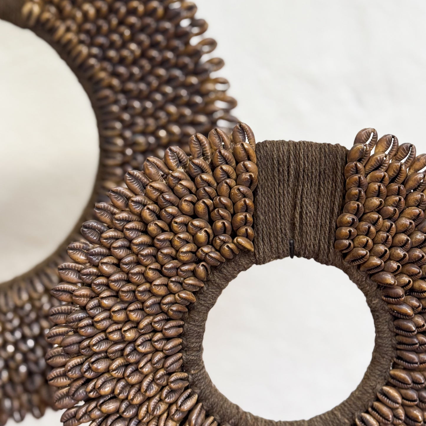 Close-up of a decorative wreath made with brown beads and ribbons on a white background