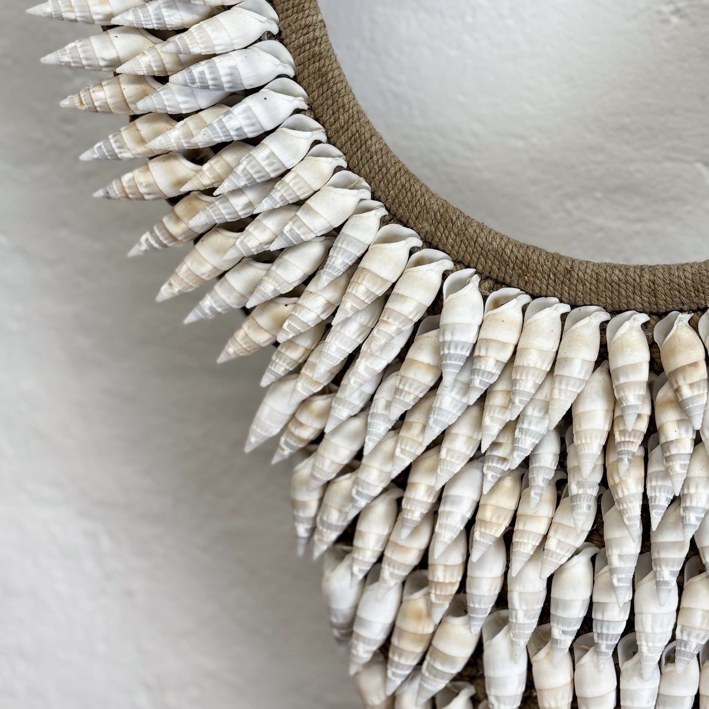 Decorative mirror with shell embellishments on a plain background