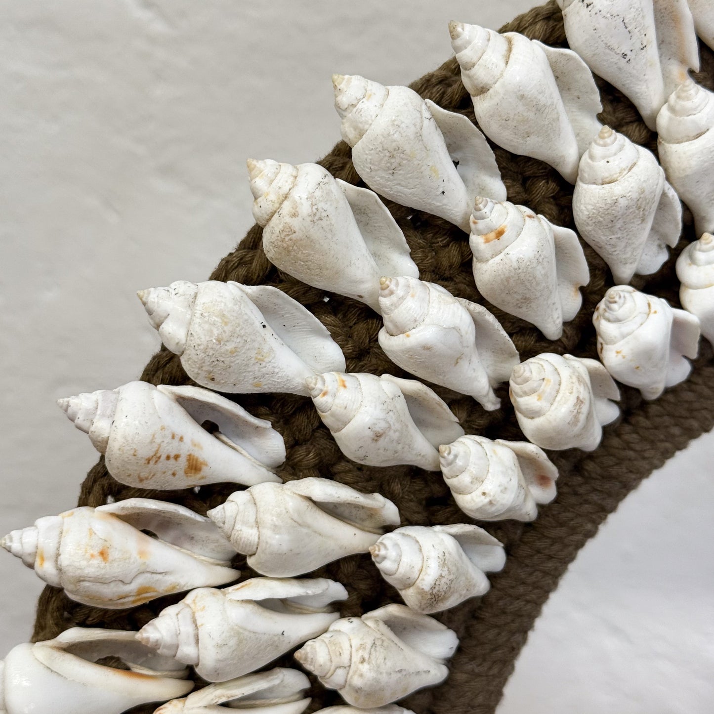 Decorative mirror with white seashells arranged on a brown rope base