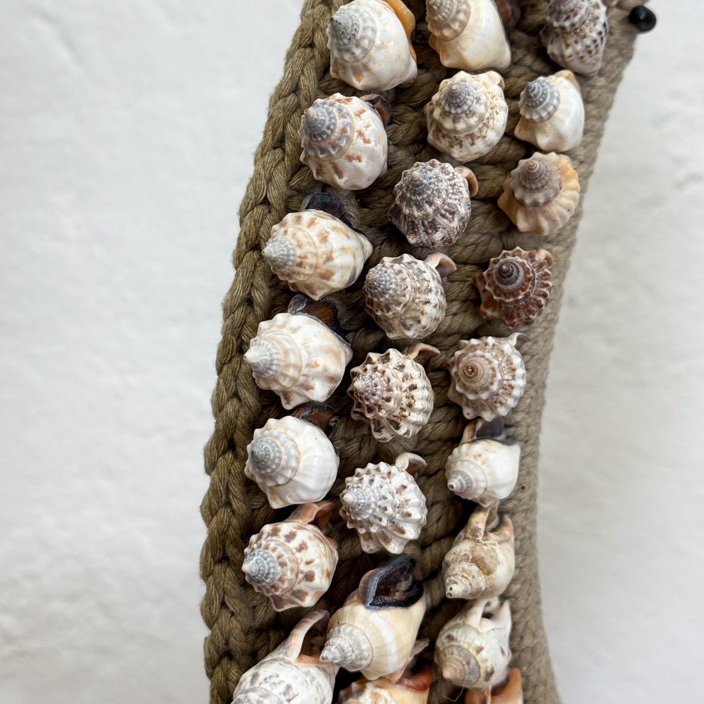 Decorative belt with braided design and seashells on a light background