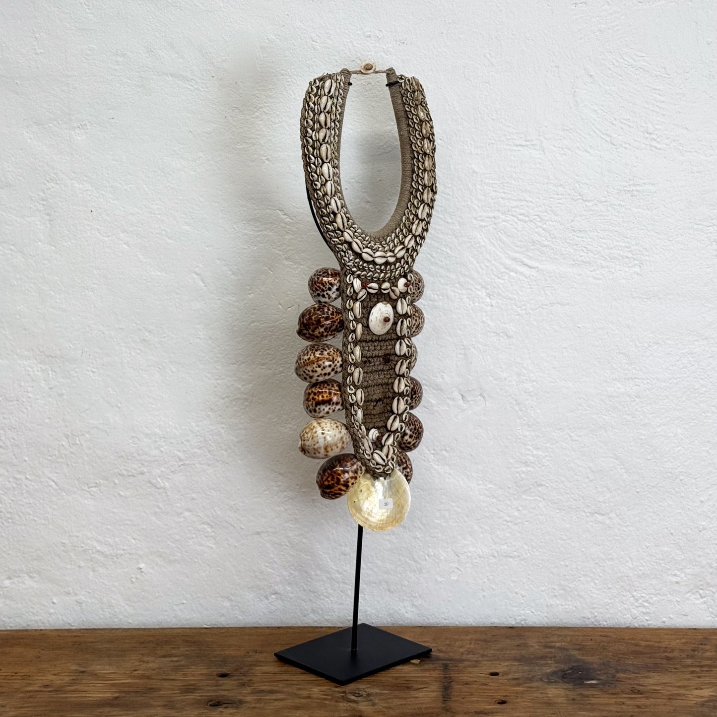 Decorative lamp with braided design and beads on a wooden surface and white wall background