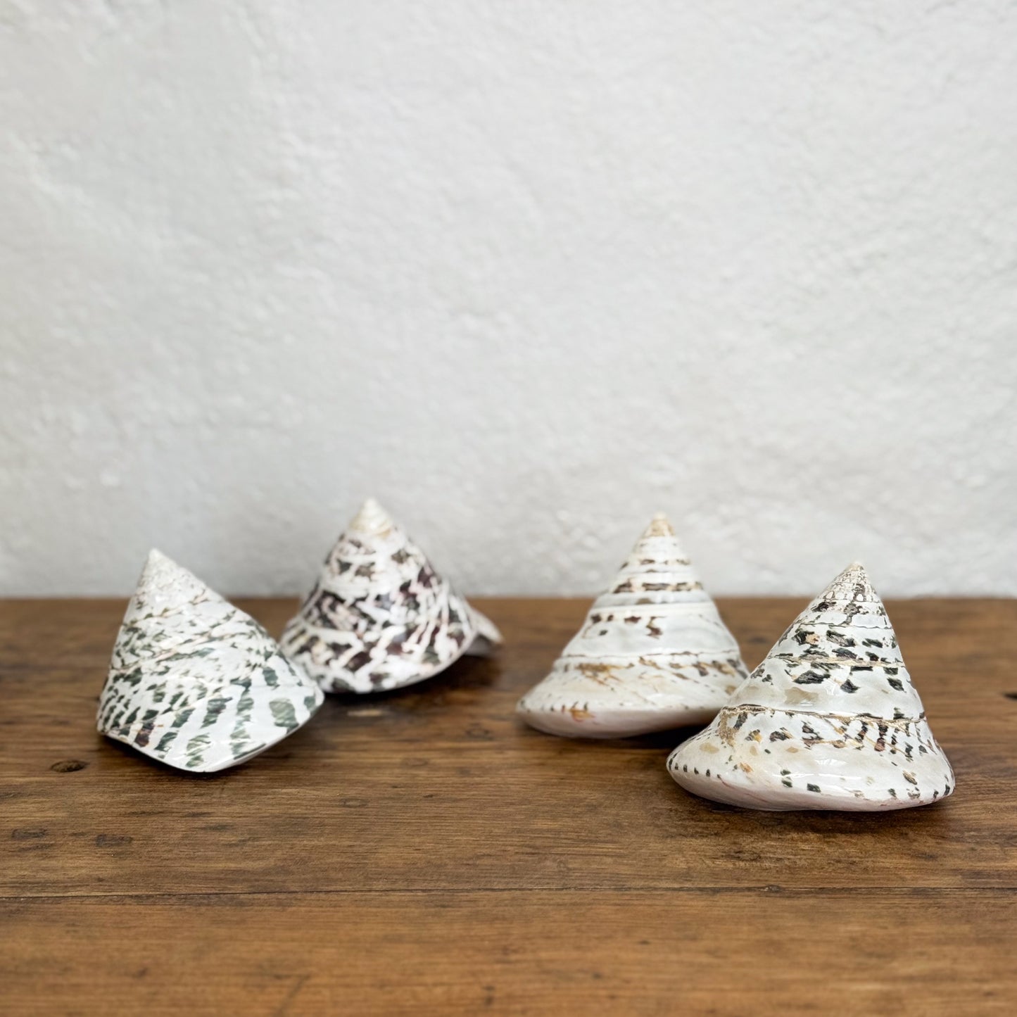 Four ceramic conical objects with textured surfaces on a wooden surface.