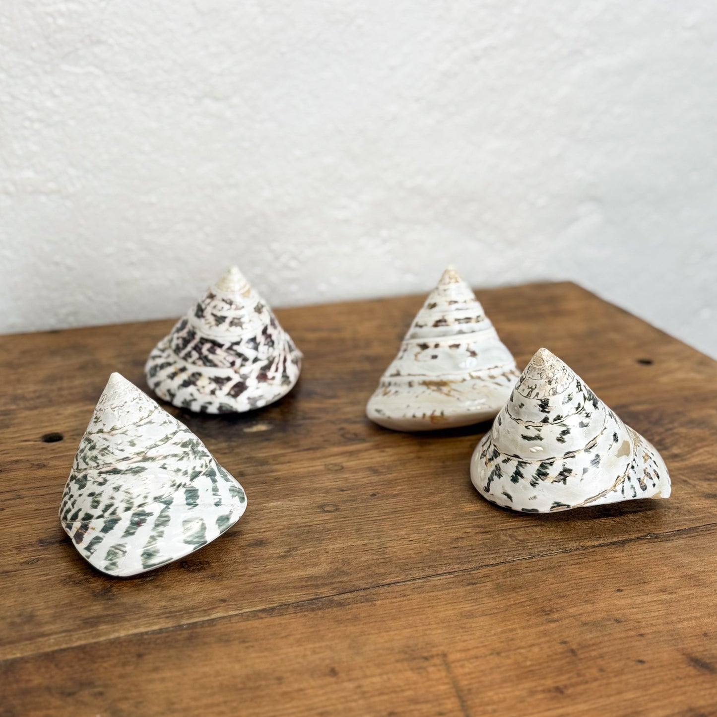 Four conical ceramic decorations with textured surfaces on a wooden surface.