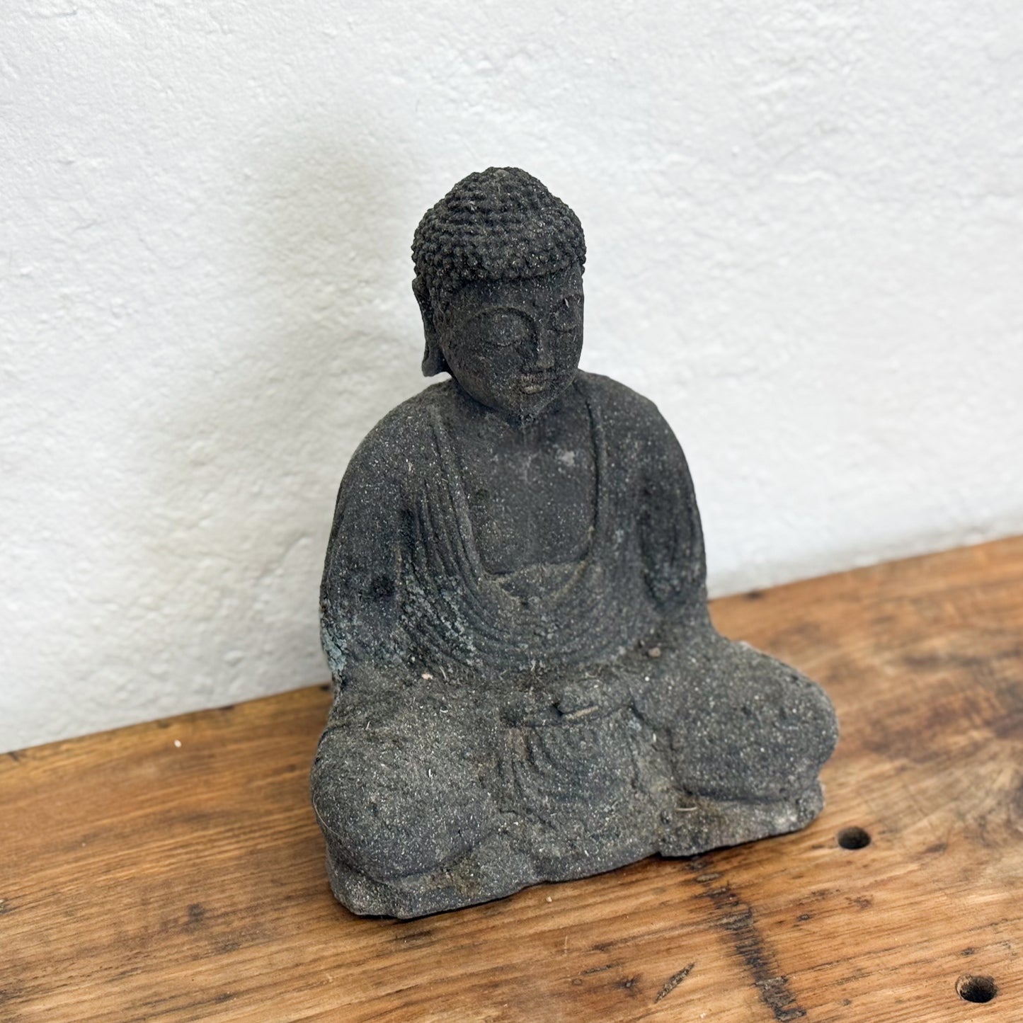 Stone Buddha statue on a wooden surface 