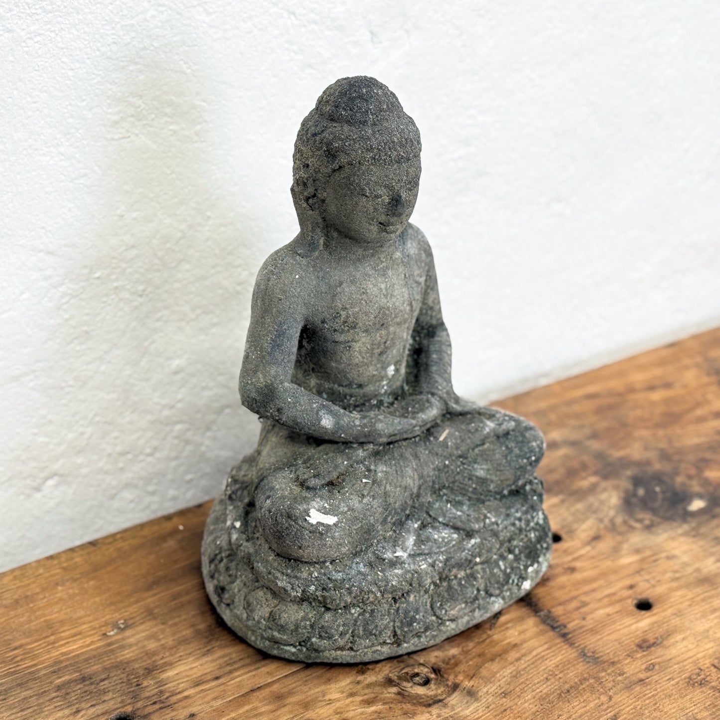 Stone Buddha statue on a wooden surface with a white background