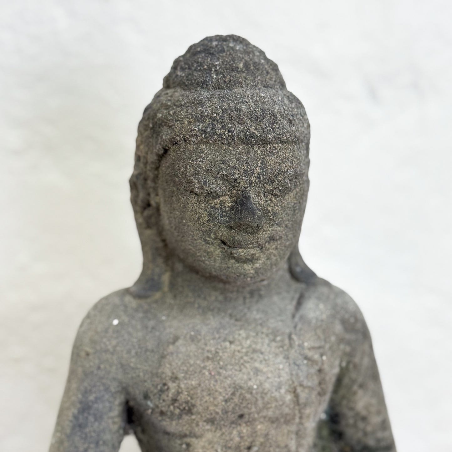 Stone statue of a seated figure on a white background