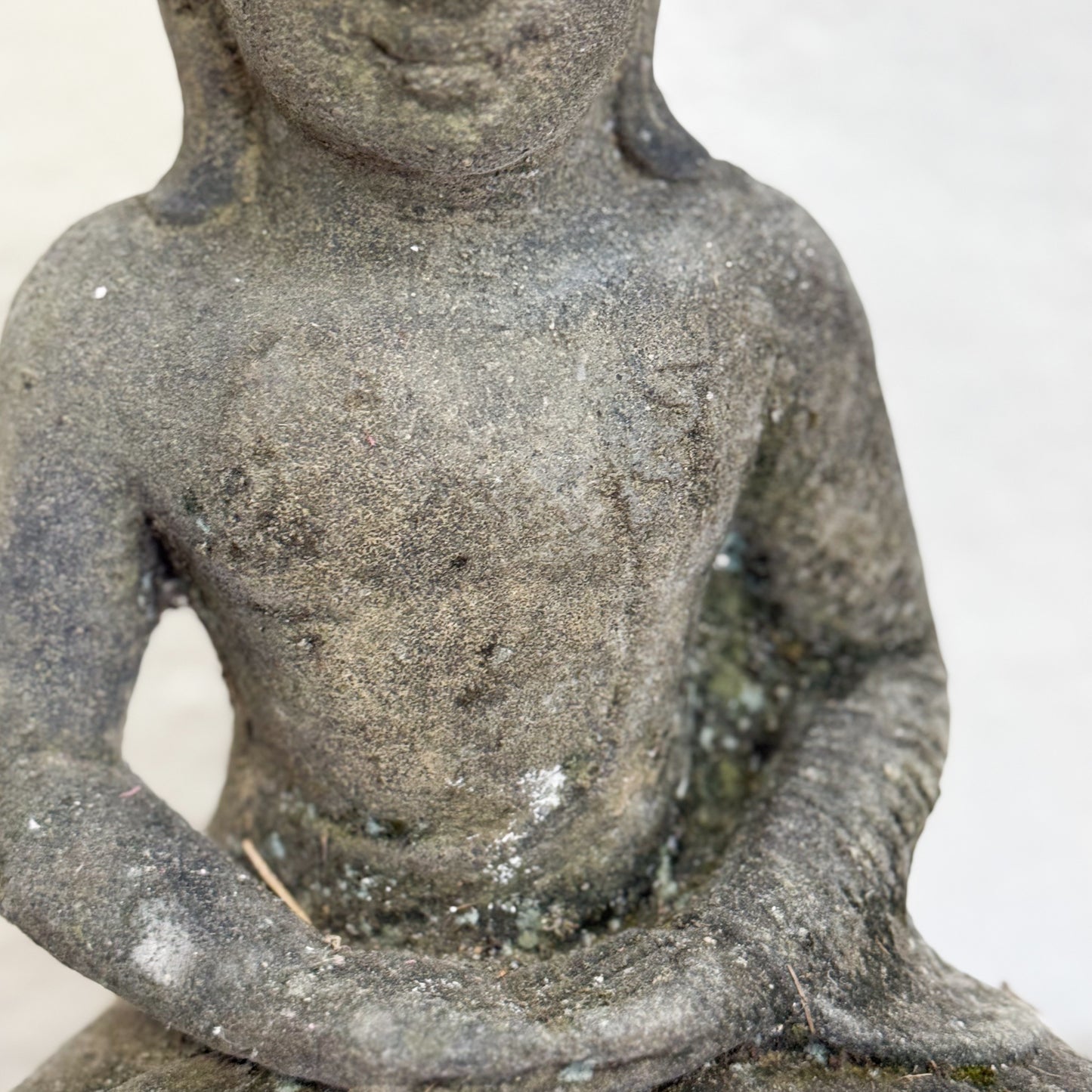 Stone sculpture of a seated figure on a plain background