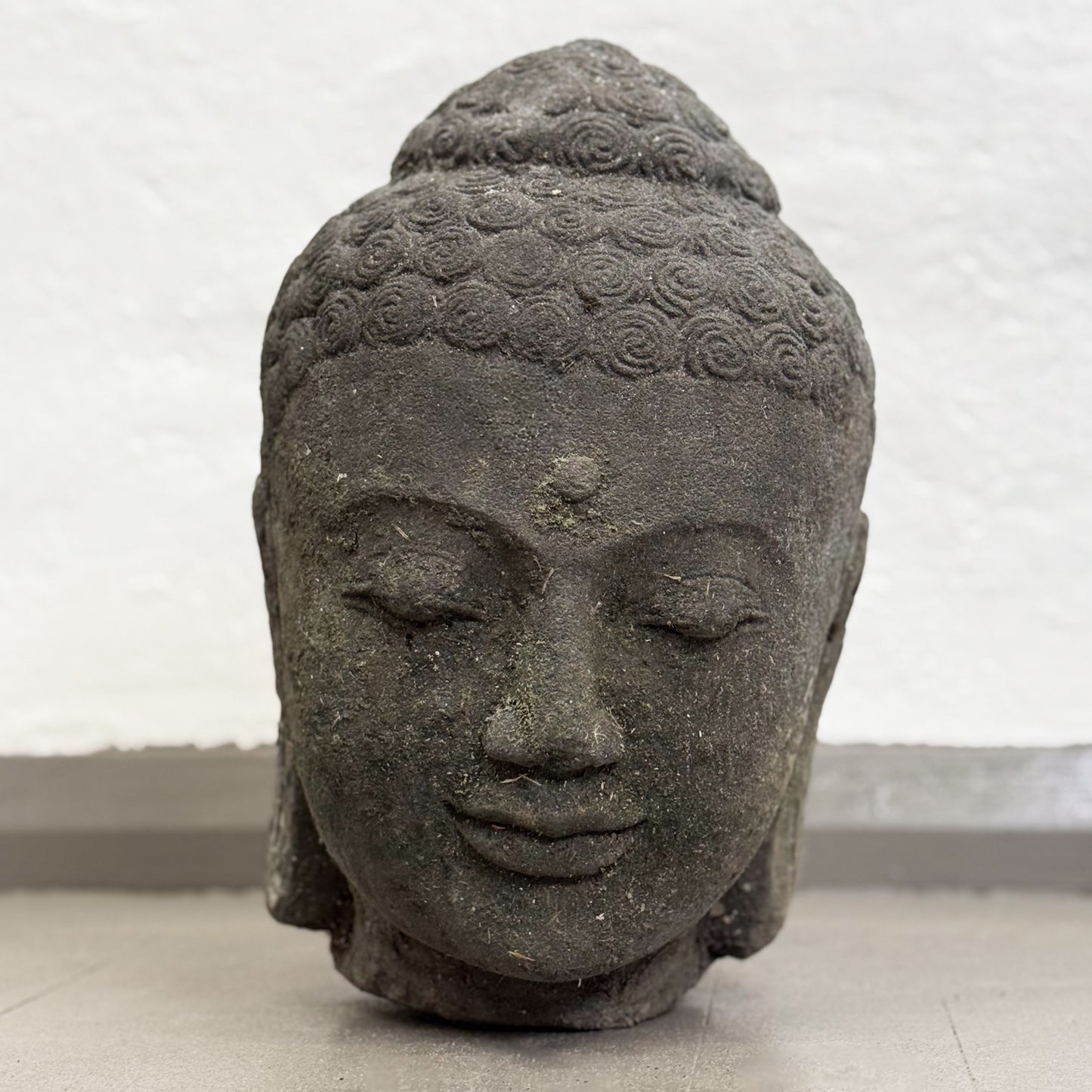 Stone sculpture of a Buddha head on a plain background