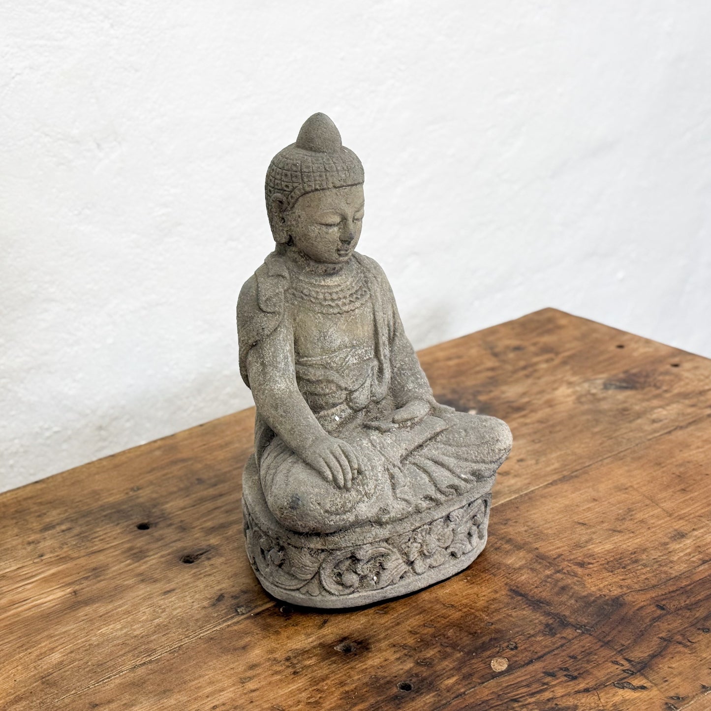 Stone Buddha statue on a wooden surface with a white background