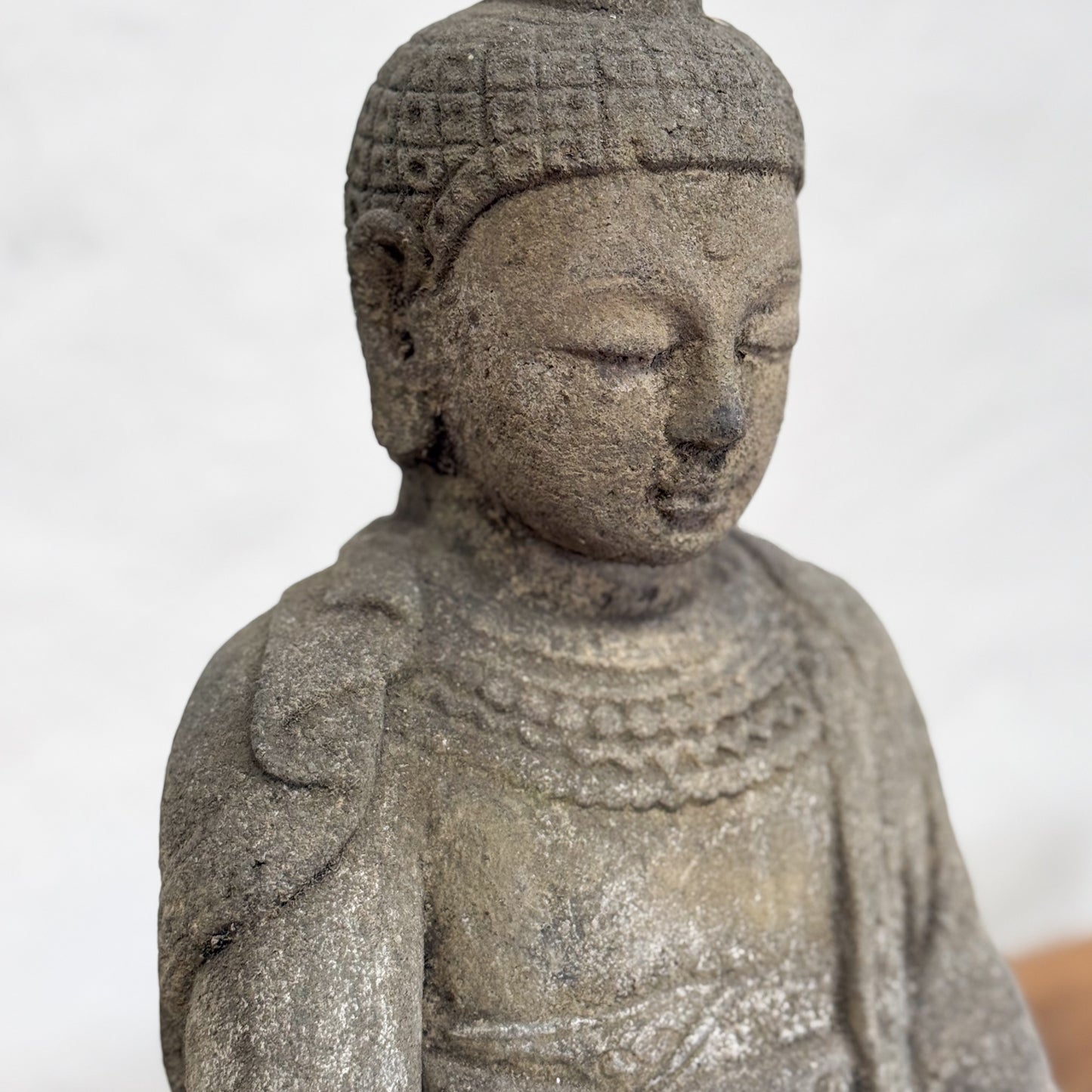 Stone statue of a seated figure with a plain background