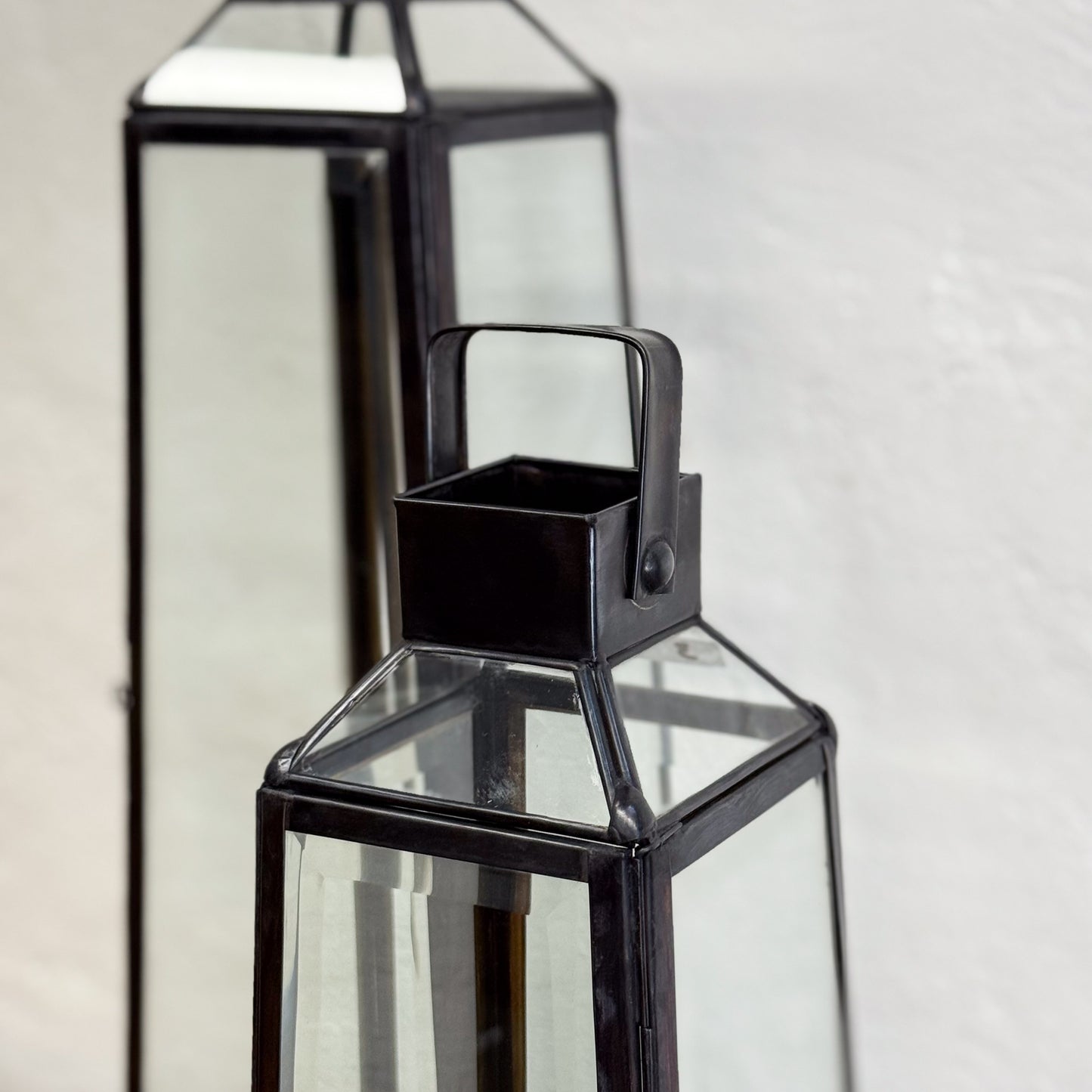 Black glass lantern with a handle on a light gray background