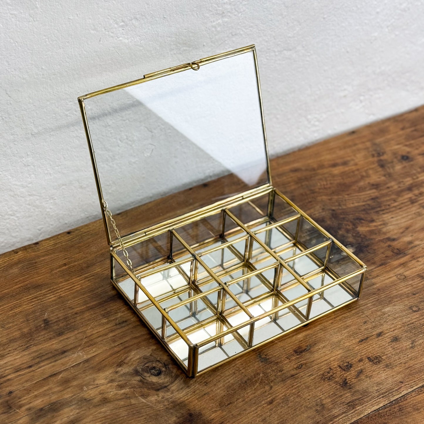 Gold jewelry box with mirror lid on a wooden surface
