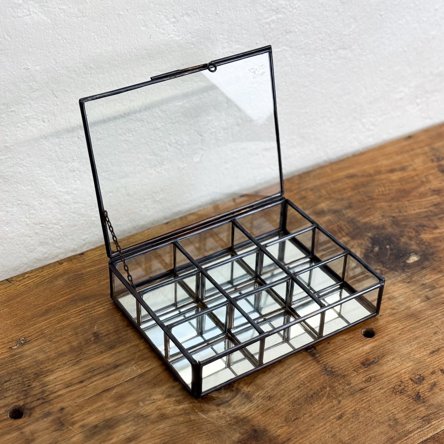 Glass display case with metal frame on a wooden surface