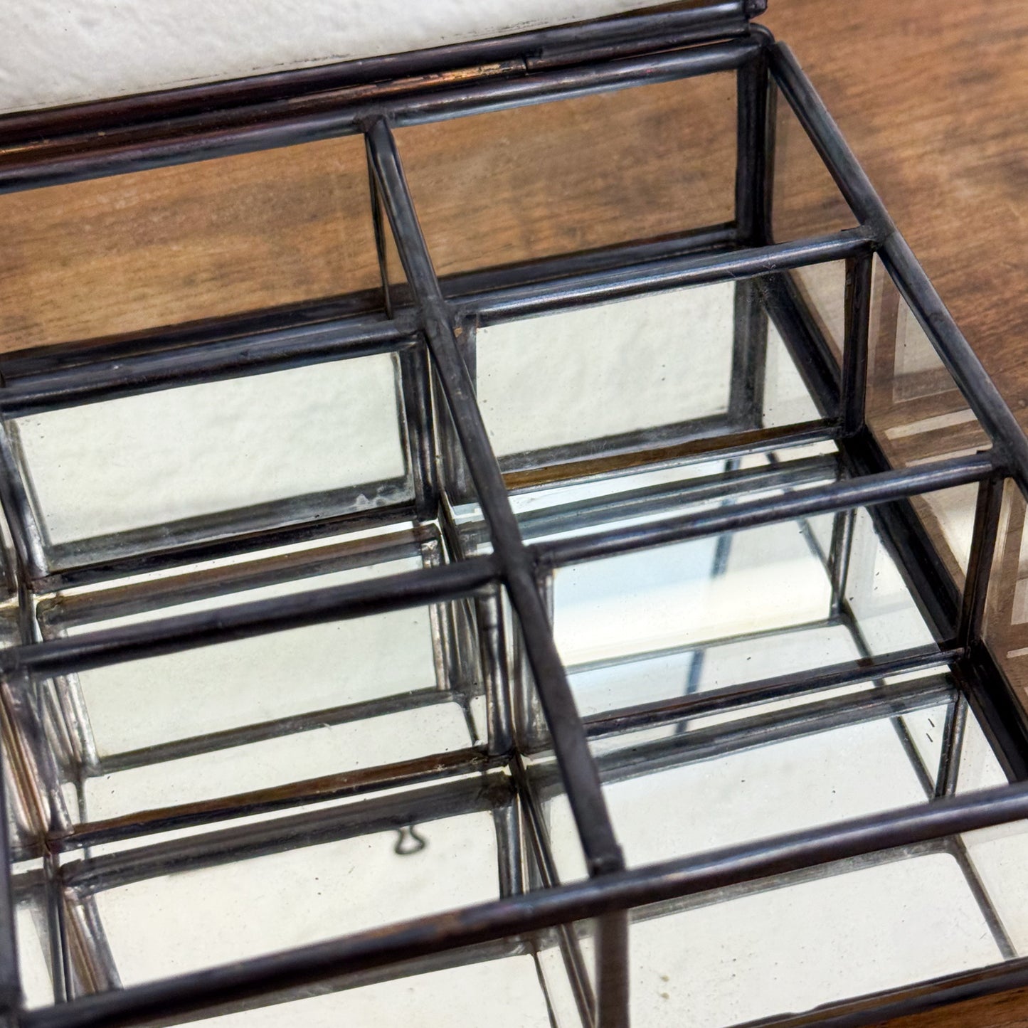 Glass display case with metal frame on a wooden surface