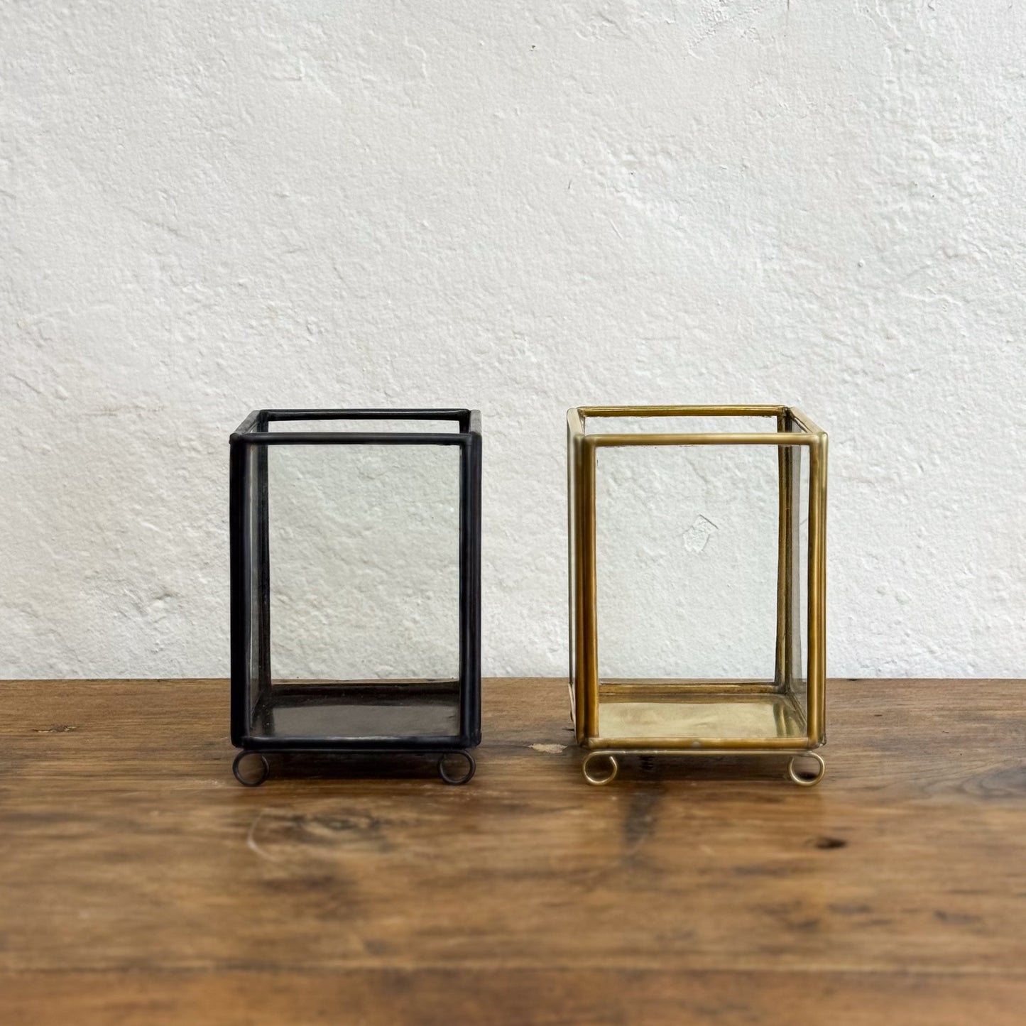 Black and gold rectangular frames on a wooden surface with a white textured wall background