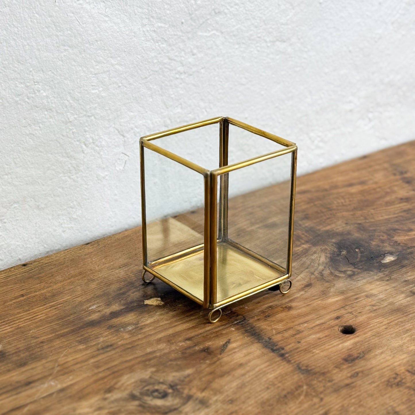 Glass container with brass frame on a wooden surface