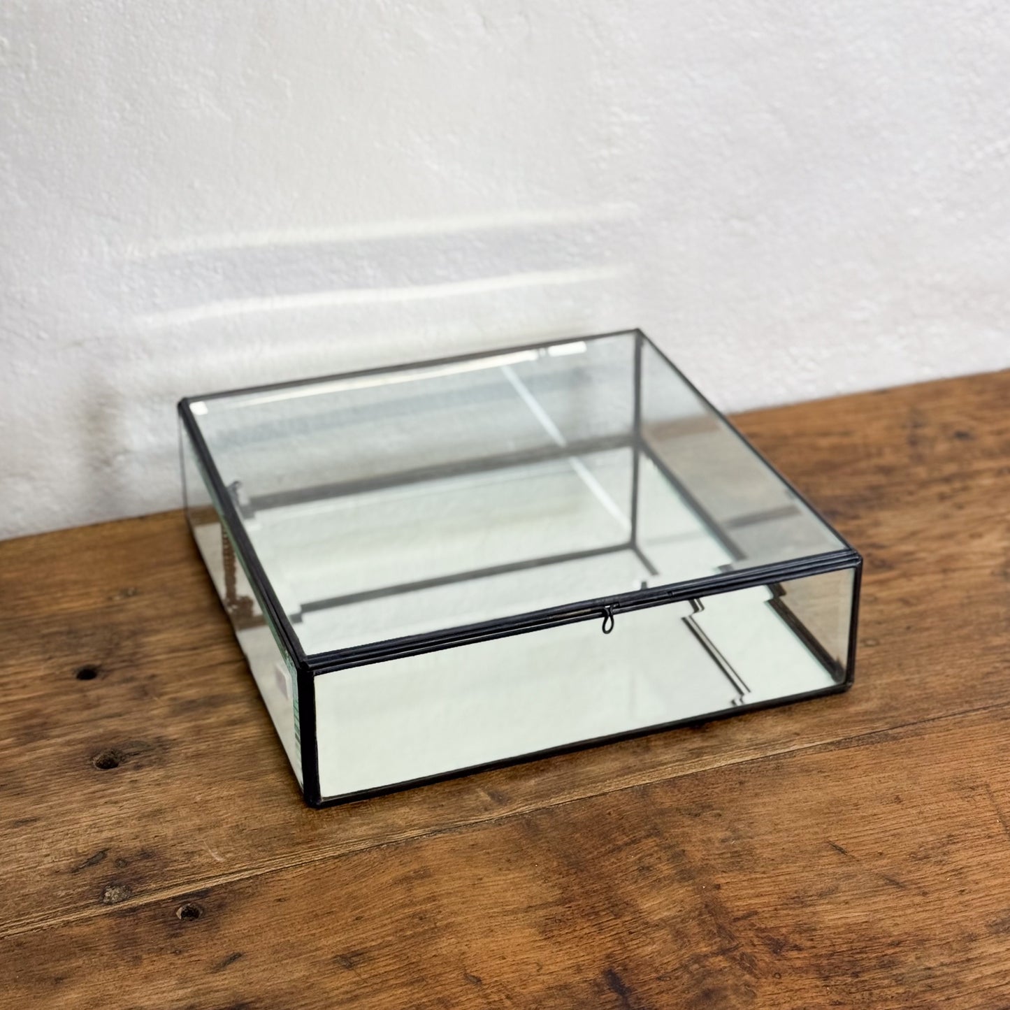 Clear glass display box on a wooden surface with a white background