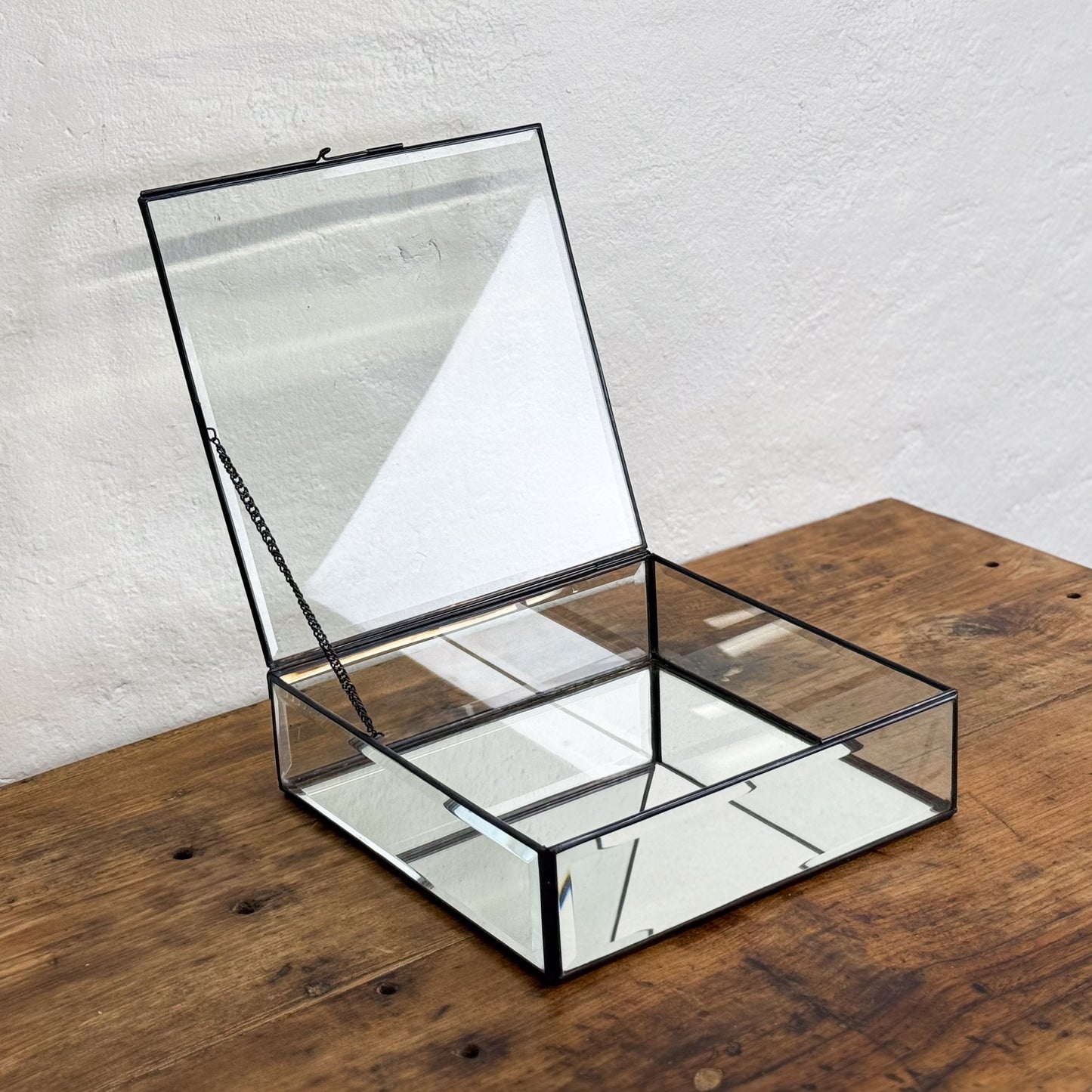 Clear glass box with black metal frame on a wooden surface