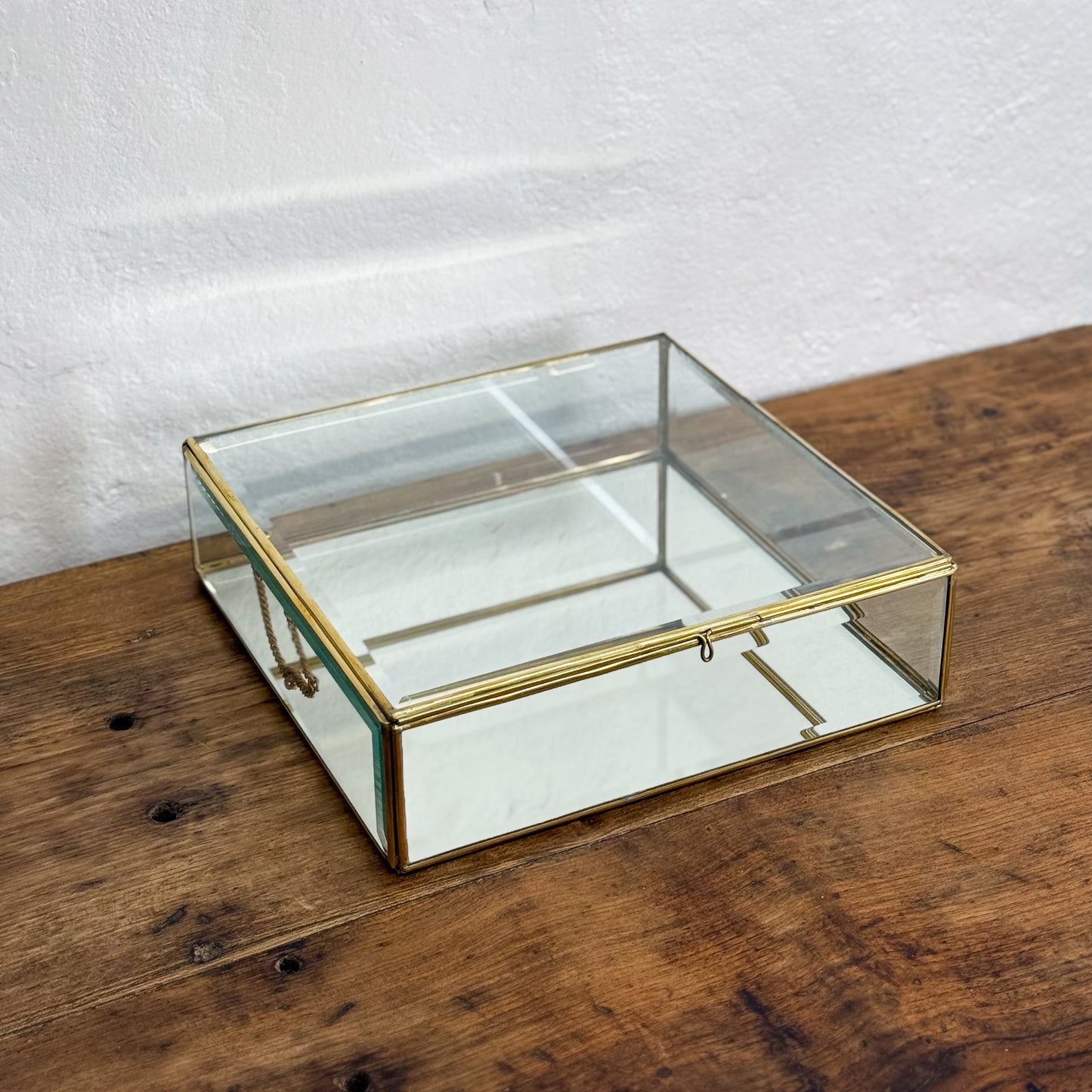 Glass display box with gold trim on a wooden surface