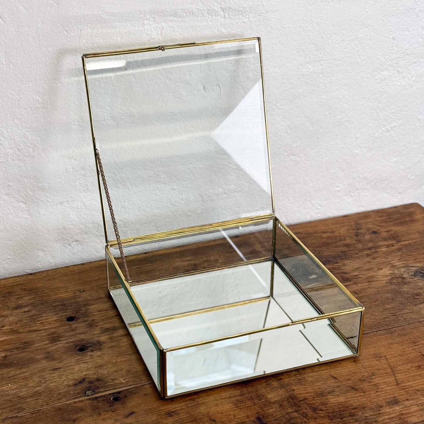 Glass jewelry box with gold trim on a wooden surface