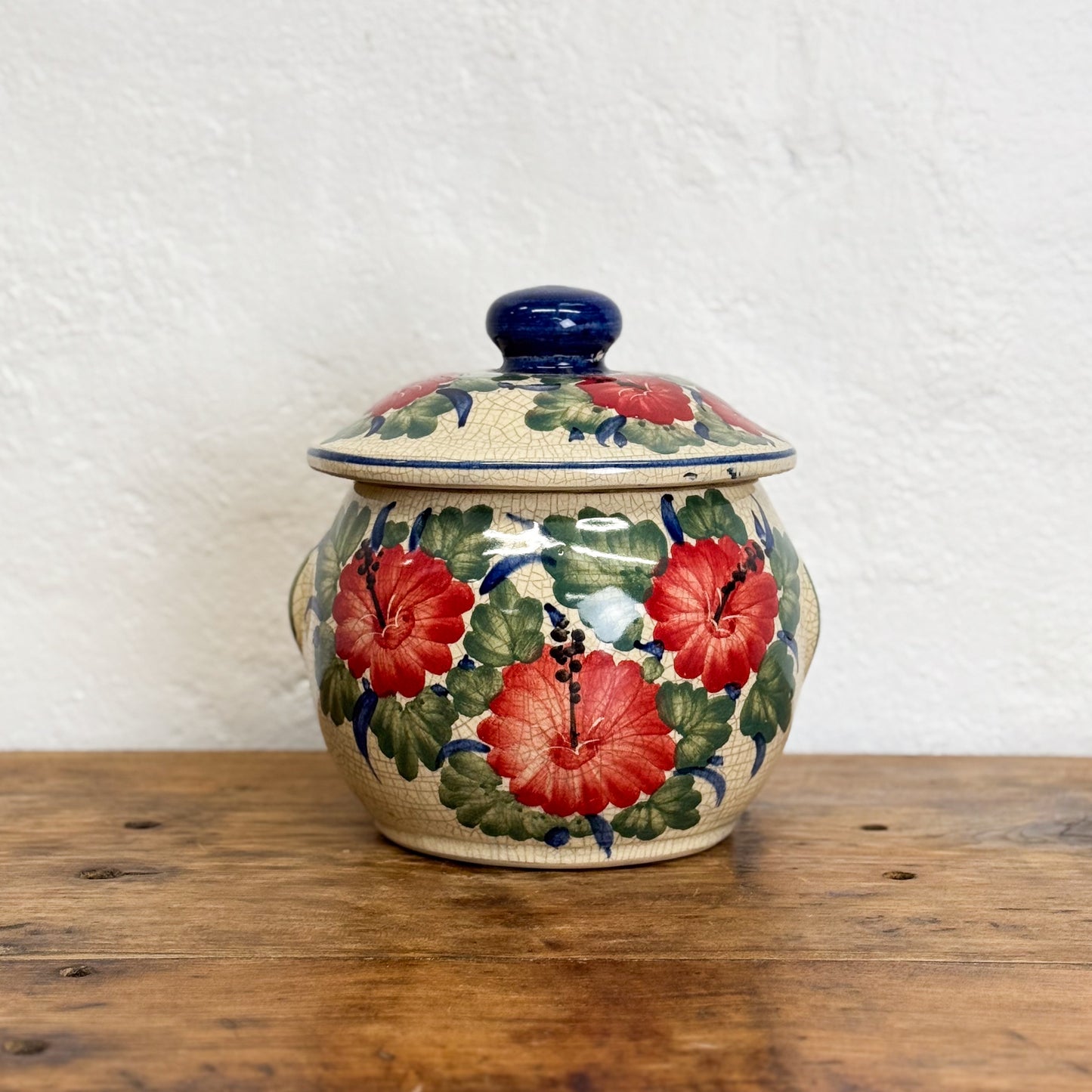 Ceramic jar with floral design on a wooden surface and white background