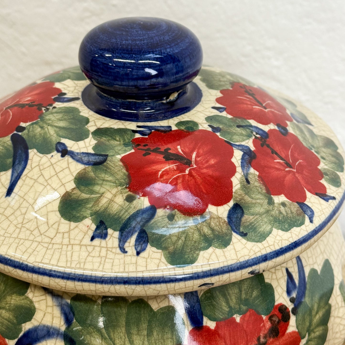 Ceramic container with floral design and blue lid on a white background