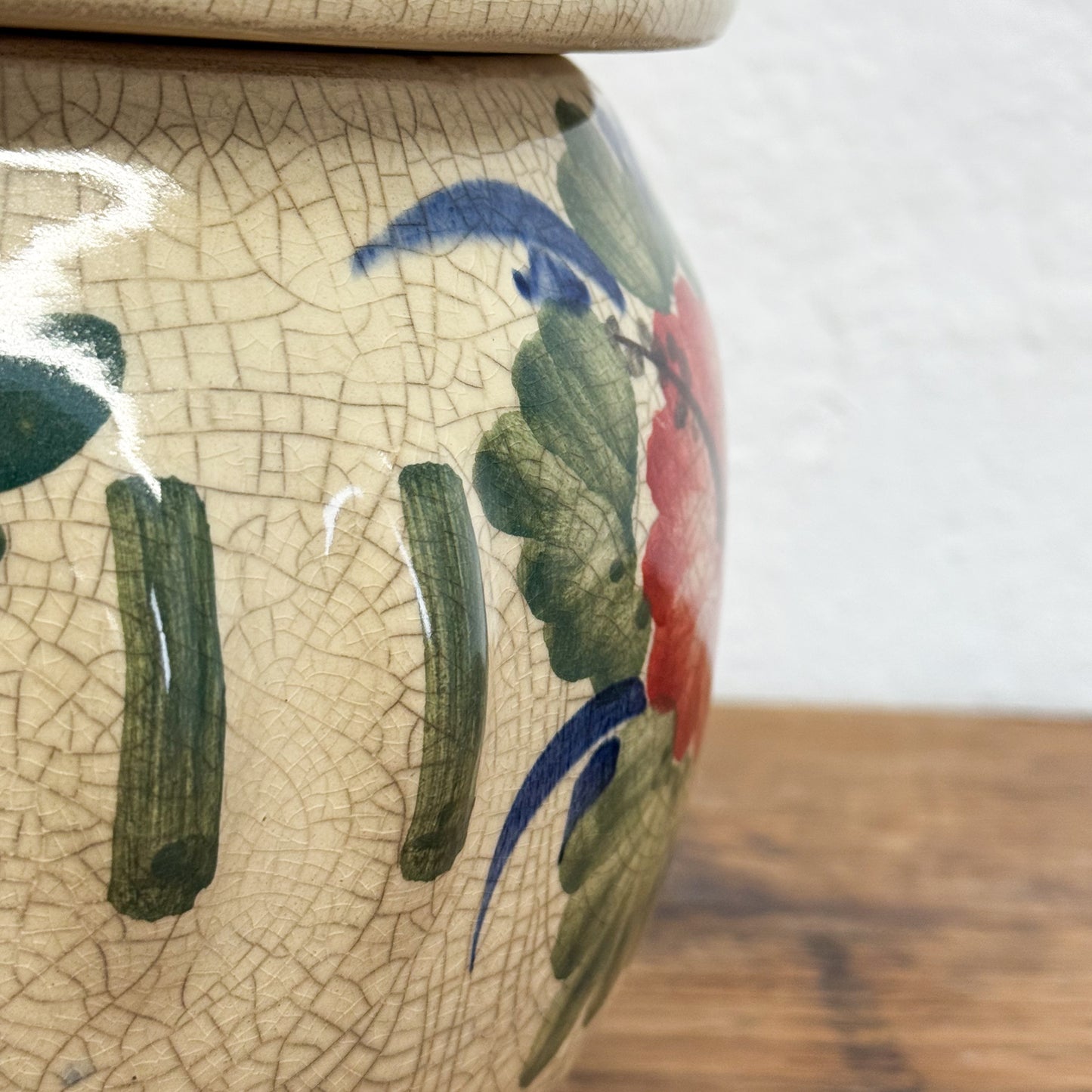 Close-up of a ceramic vase with floral designs and a cracked glaze texture.