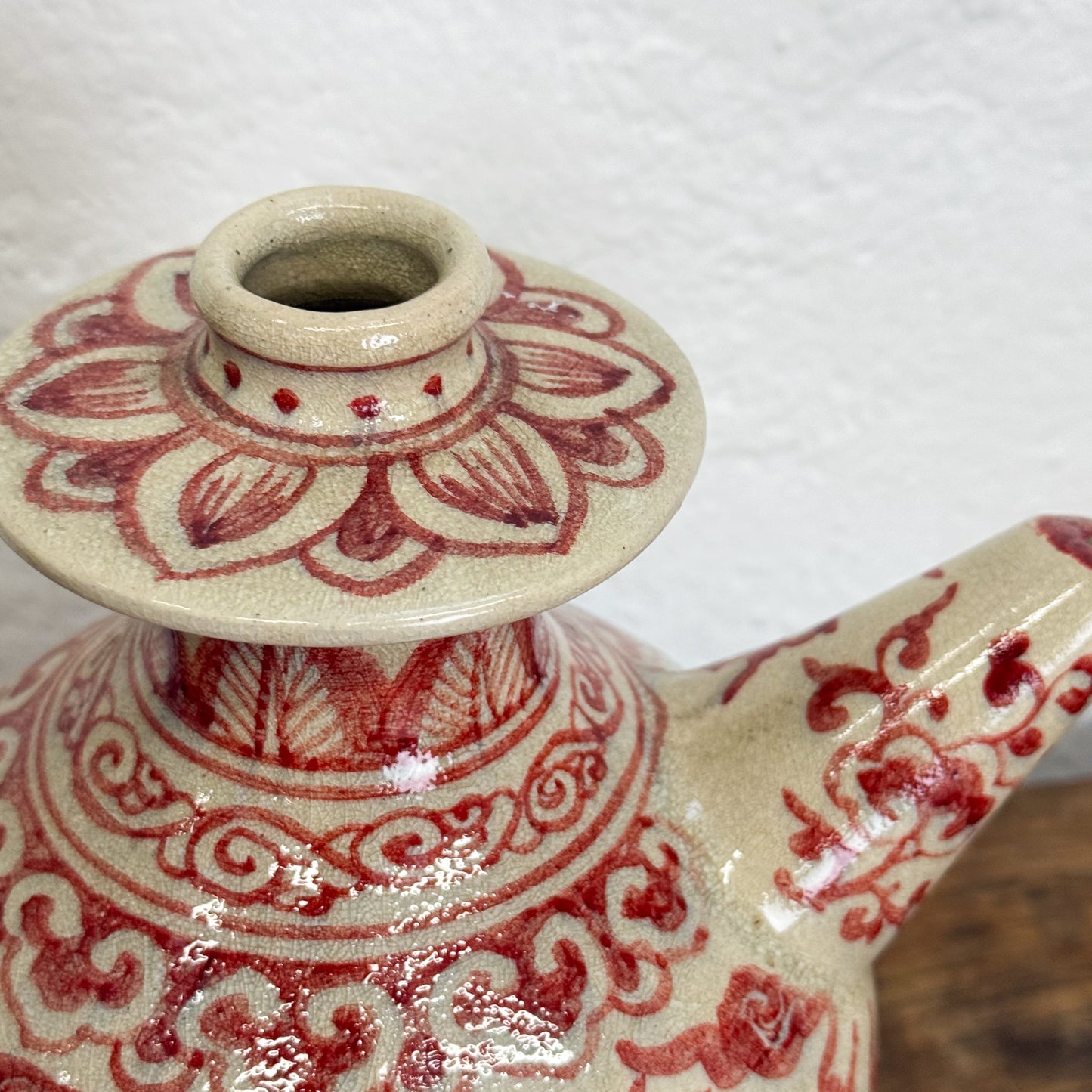 Ceramic teapot with red floral patterns on a white background