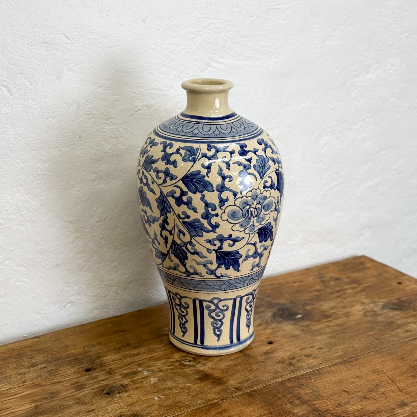 Blue and white ceramic vase on a wooden surface with a white wall background