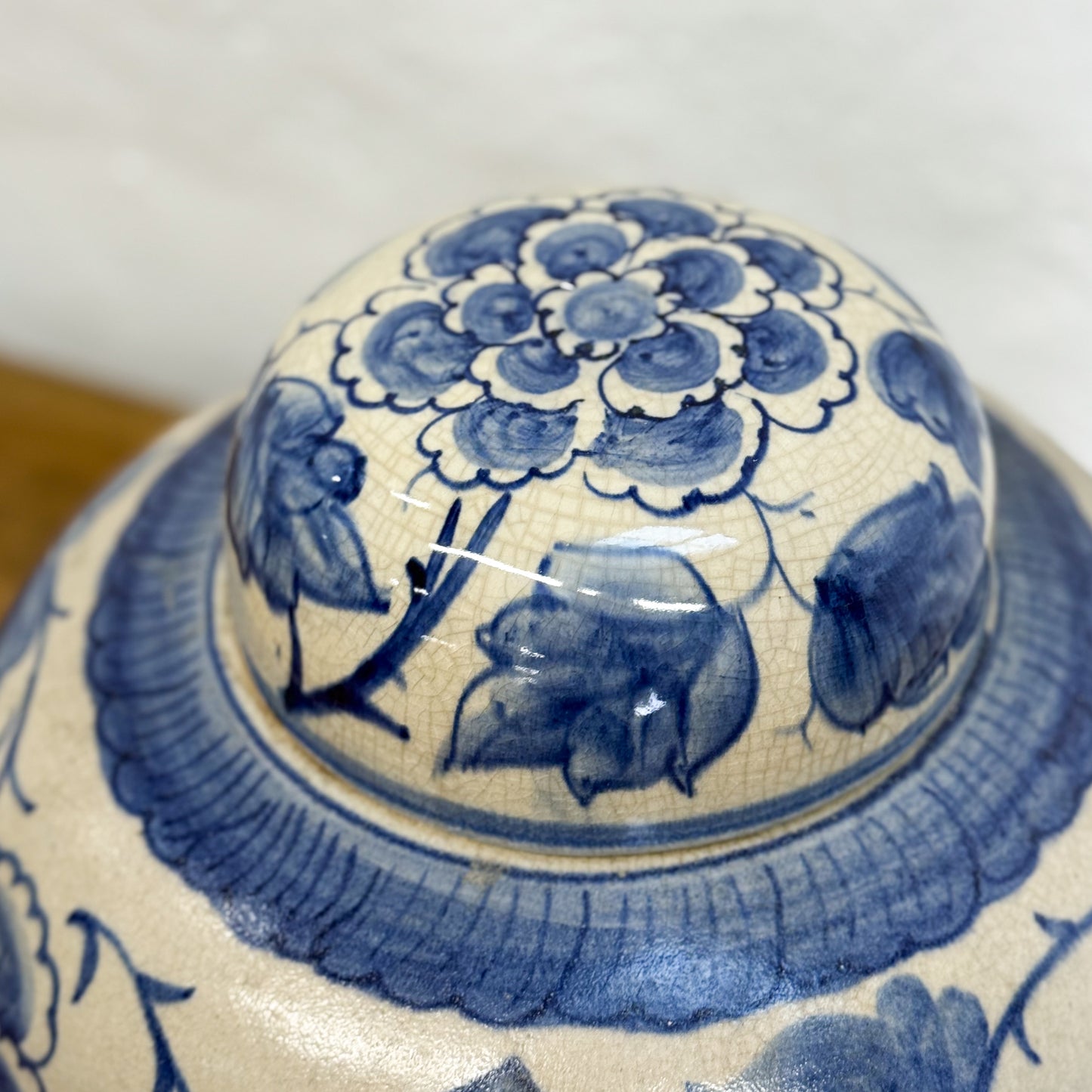Close-up of a blue and white ceramic lid with floral and animal designs.
