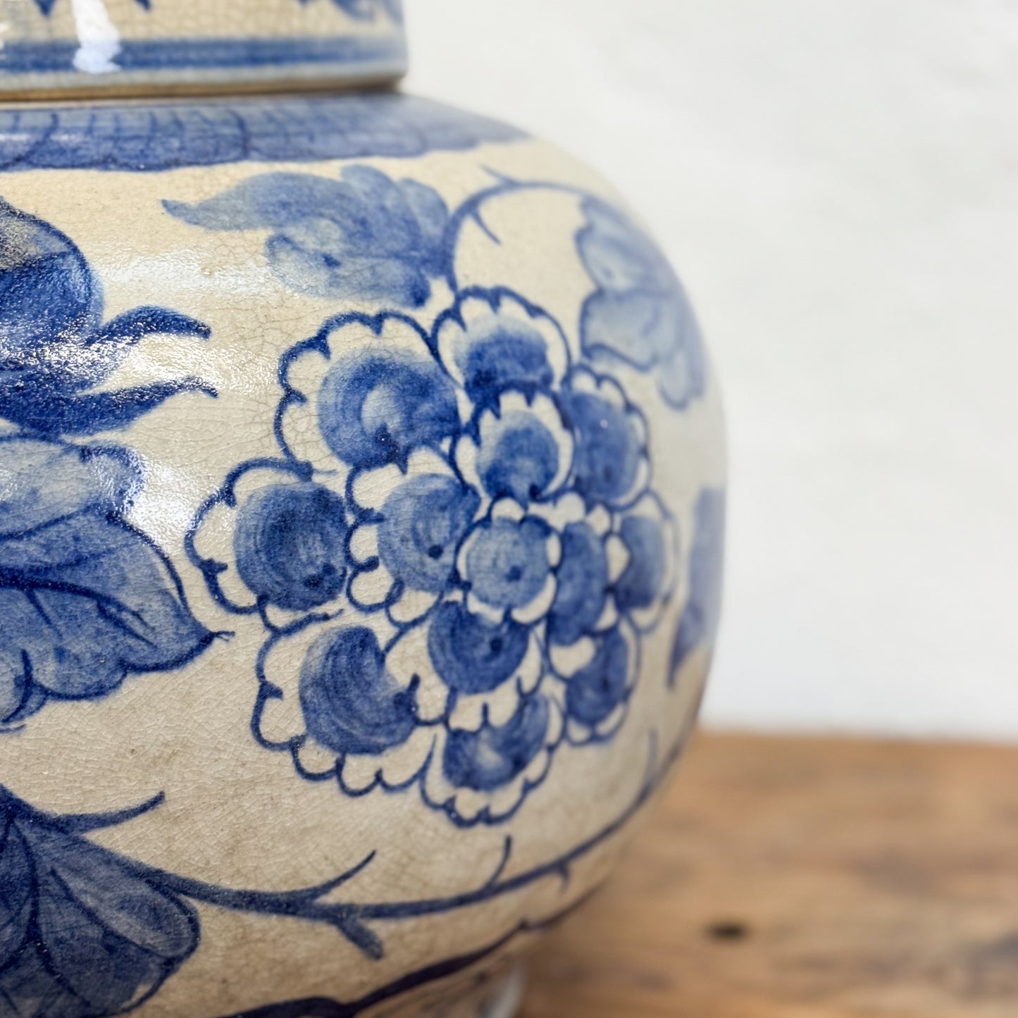 Close-up of a blue and white floral-patterned ceramic jar on a wooden surface.