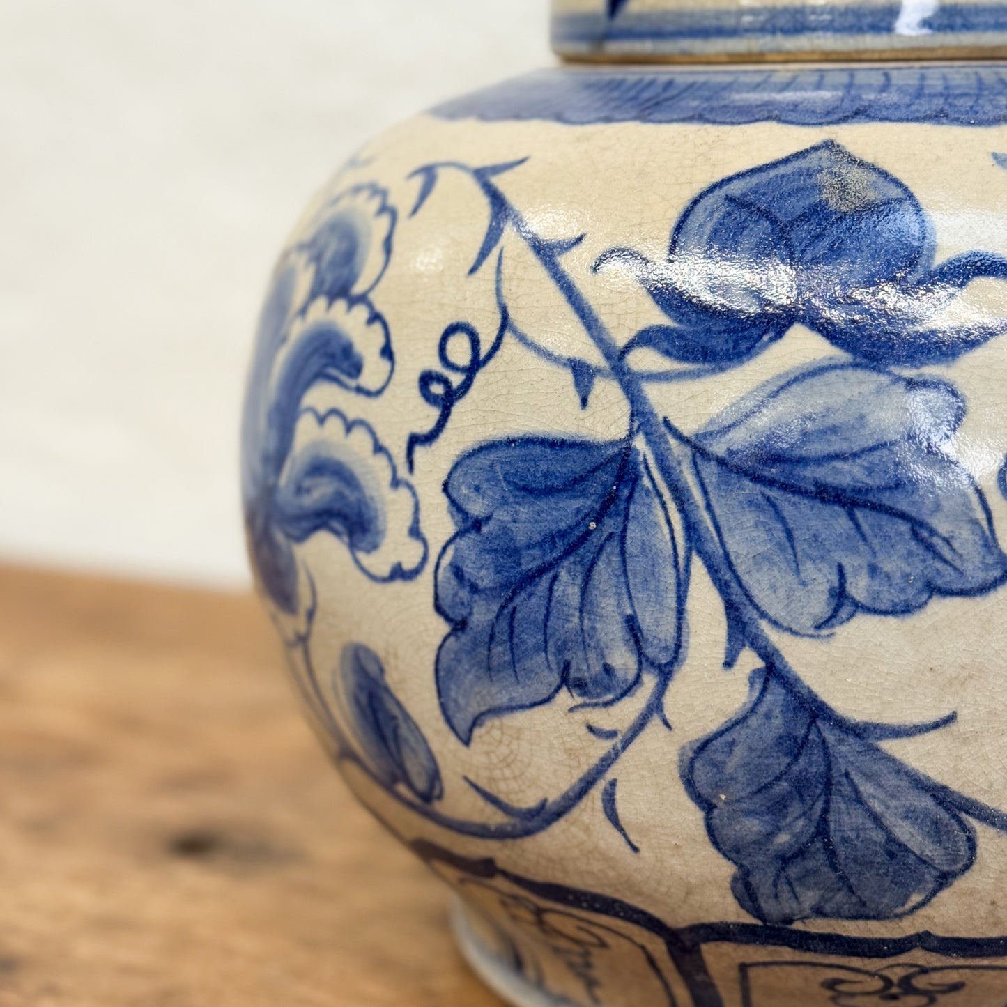 Close-up of a ceramic jar with blue floral patterns on a wooden surface.