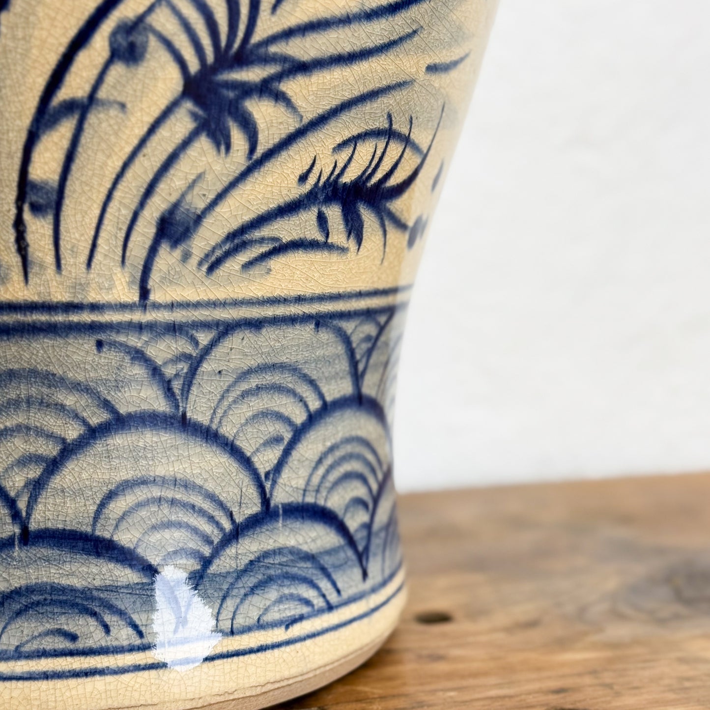 Ceramic vase with blue floral and wave patterns on a wooden surface