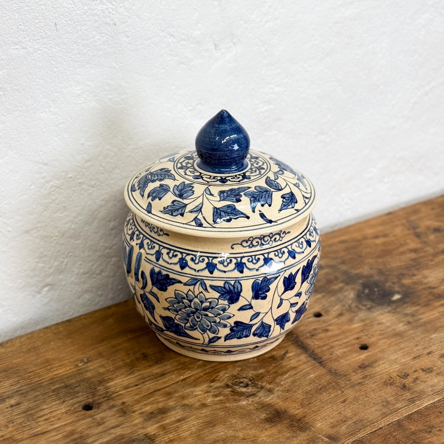Ceramic jar with blue floral patterns on a wooden surface
