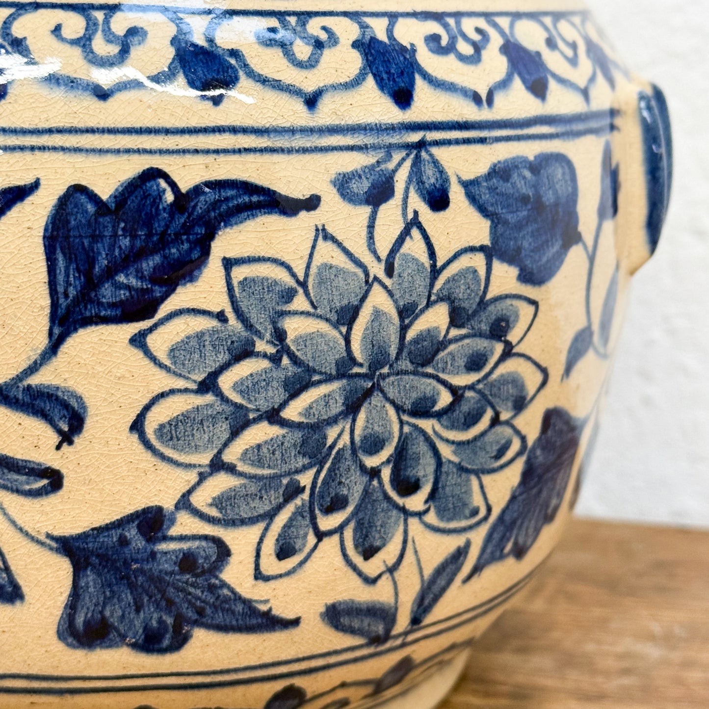 Close-up of a ceramic jar with blue floral patterns on a wooden surface.