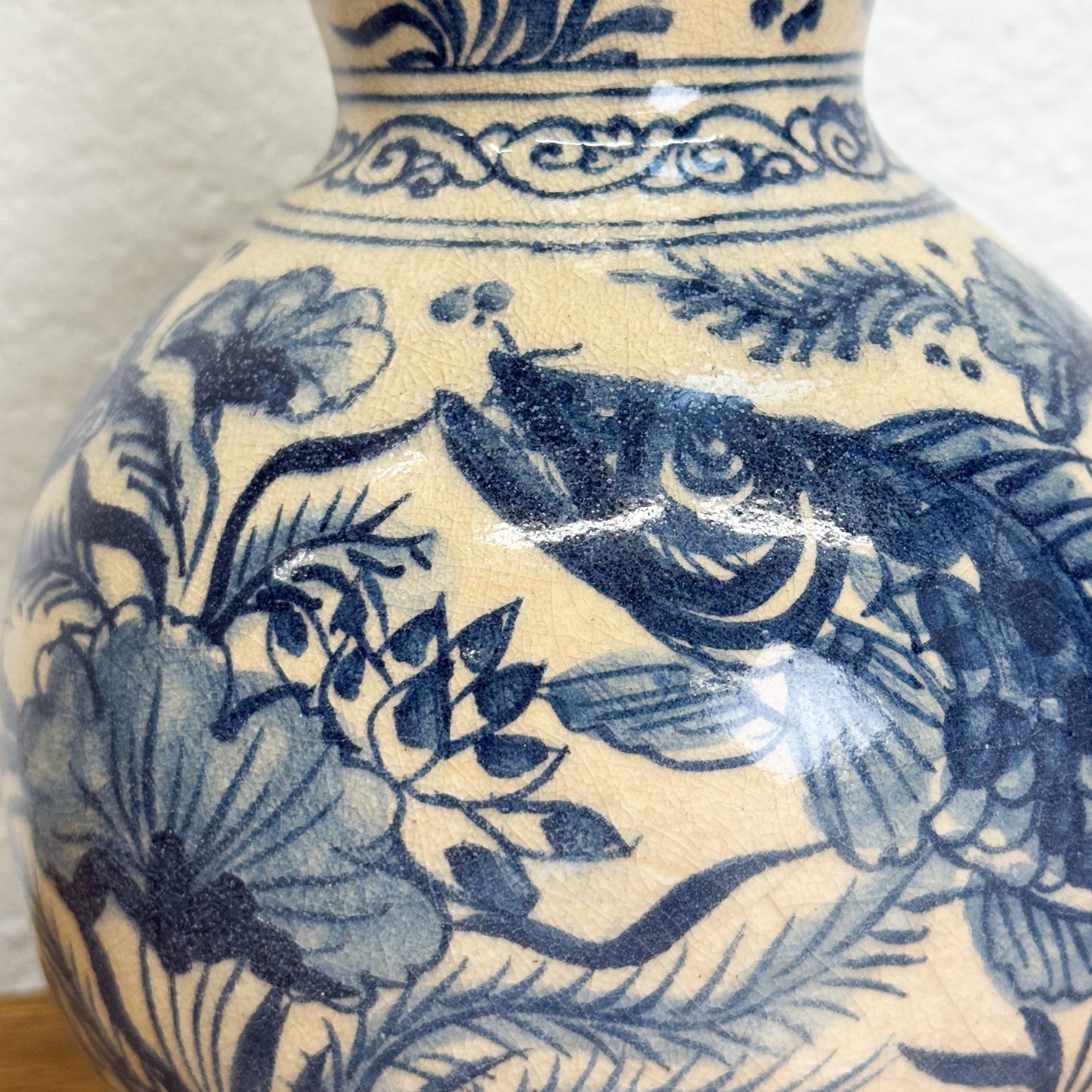 Ceramic vase with blue floral and fish design on a beige background