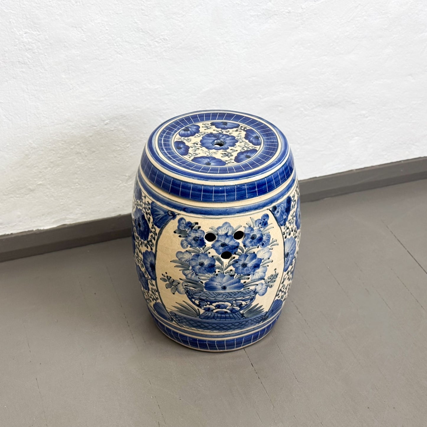 Blue and white ceramic stool with floral patterns on a plain background