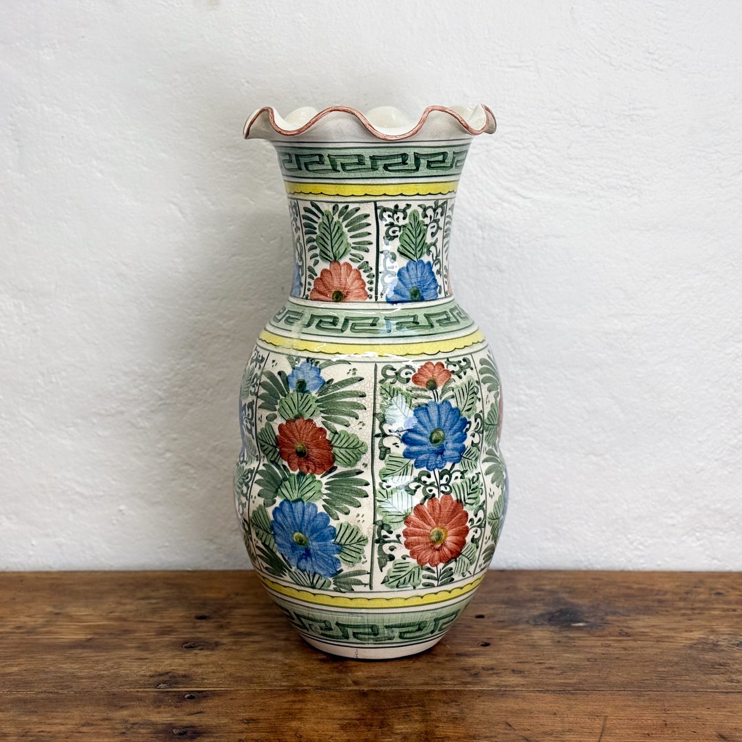 Decorative ceramic vase with floral patterns on a wooden surface and white background