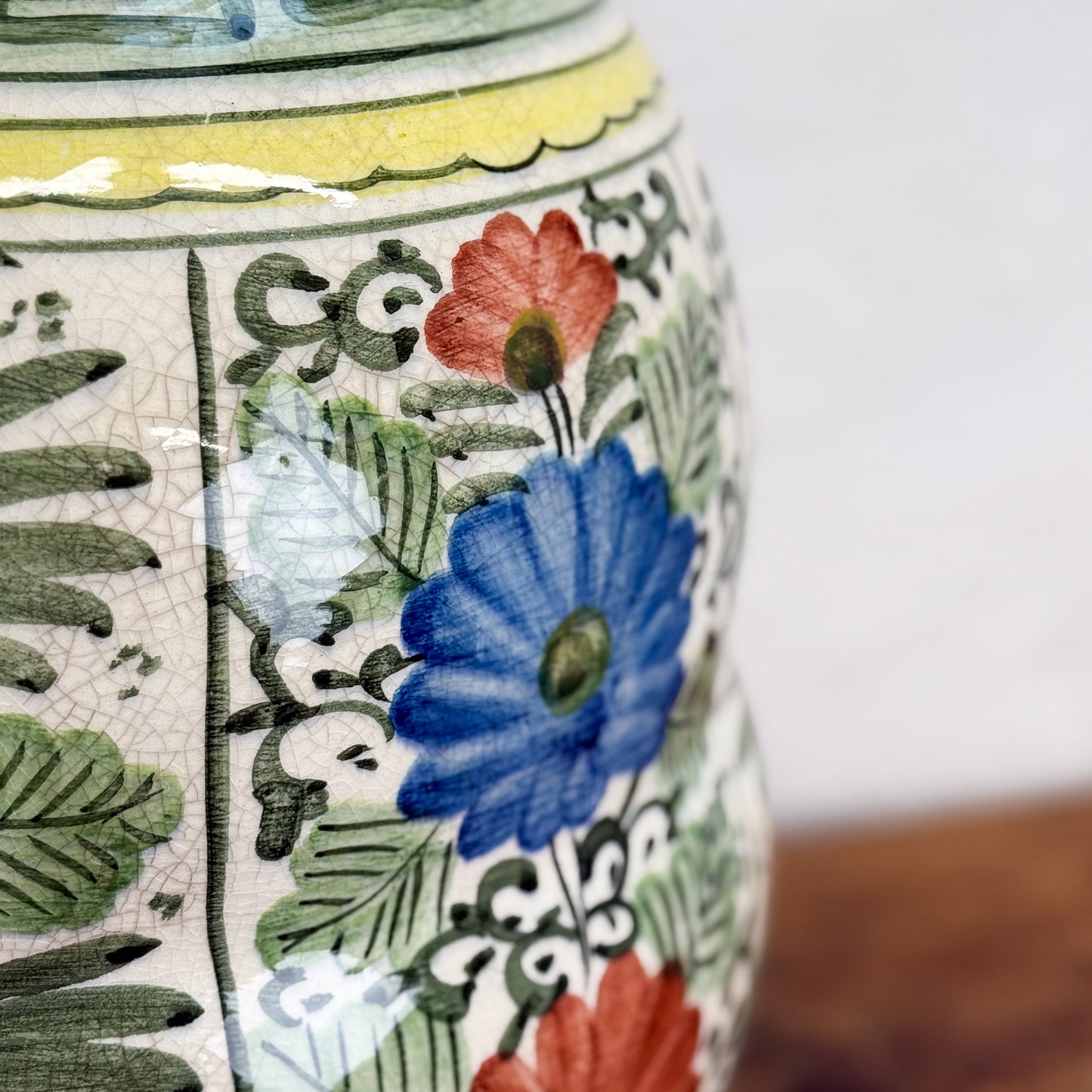 Close-up of a ceramic vase with floral and leaf patterns on a blurred background