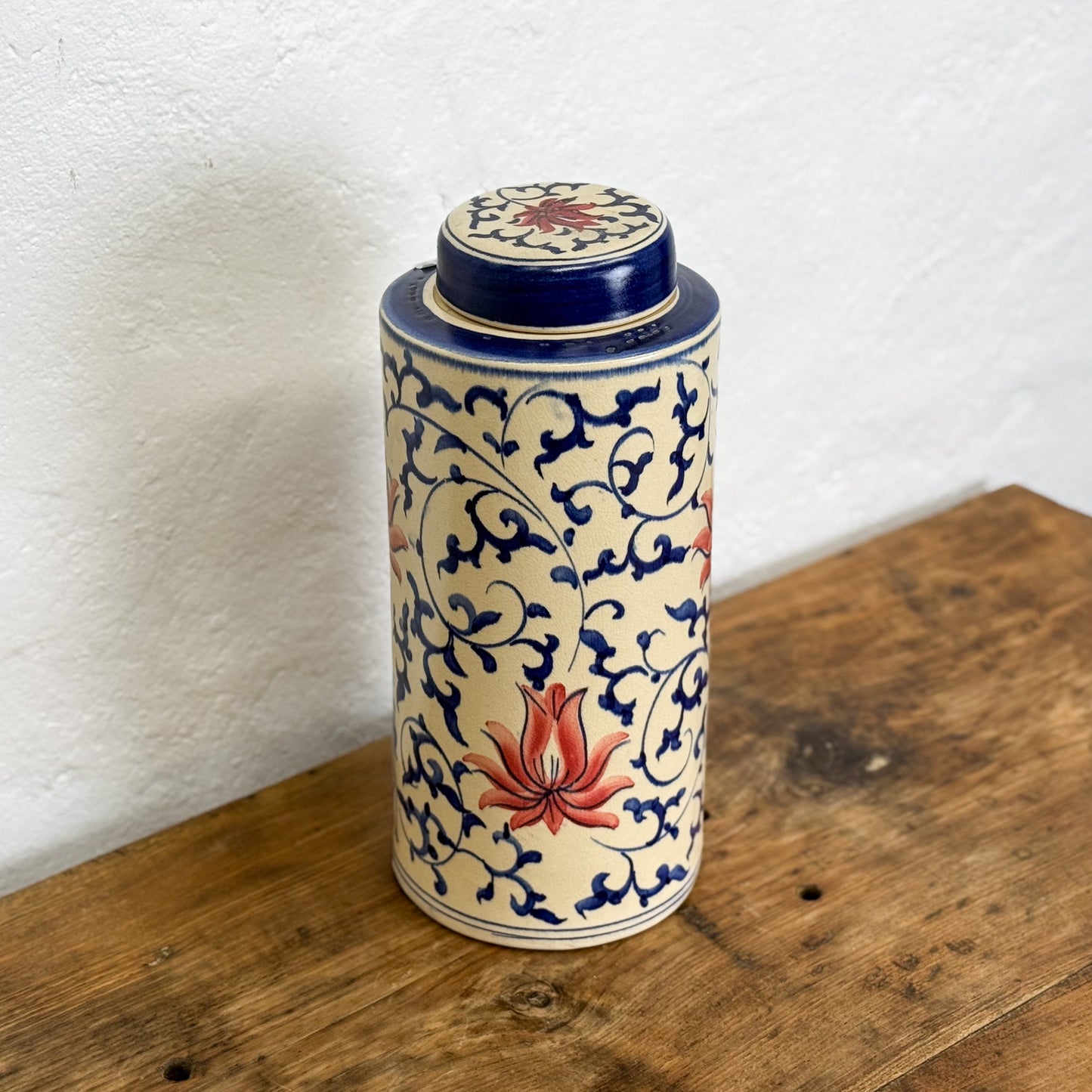 Cylindrical ceramic jar with floral design on a wooden surface