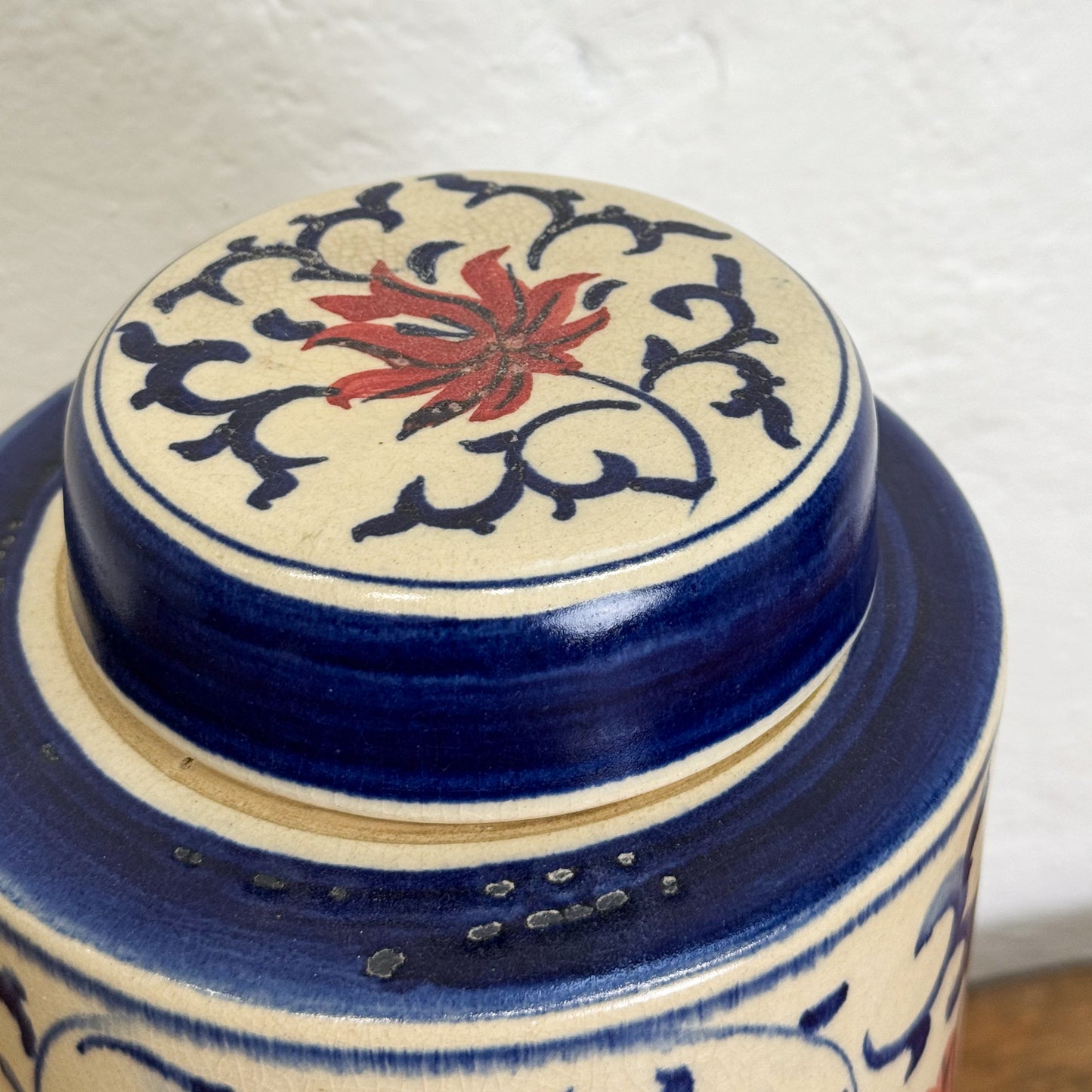 Ceramic jar with decorative lid featuring floral design on a white background