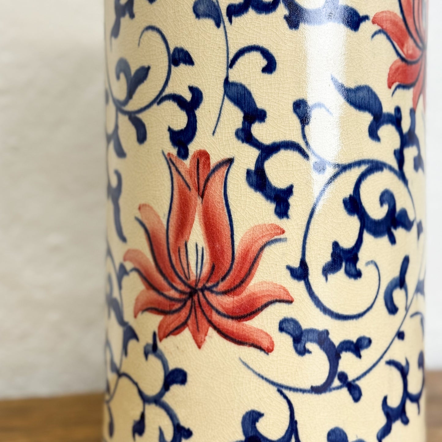 Ceramic vase with floral and scroll design on a beige background