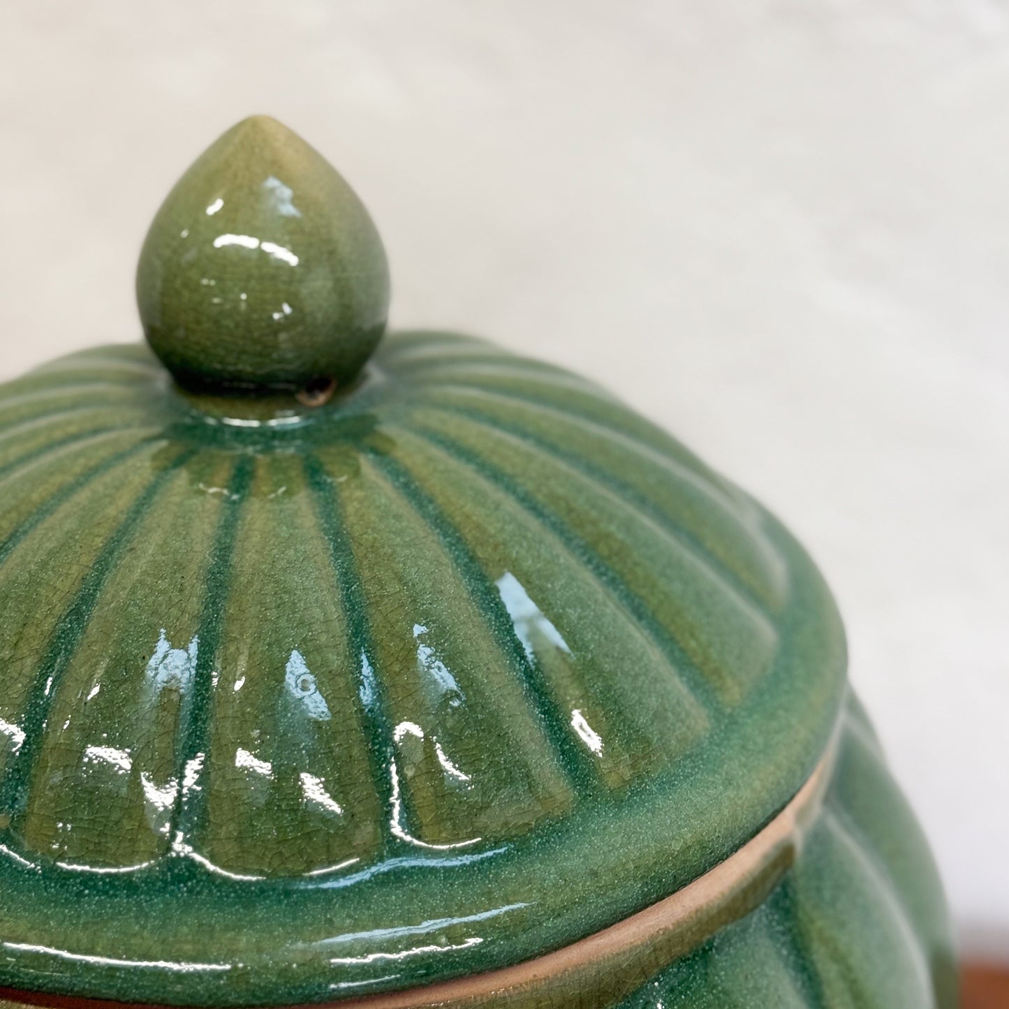 Green ceramic jar with a textured lid on a white background