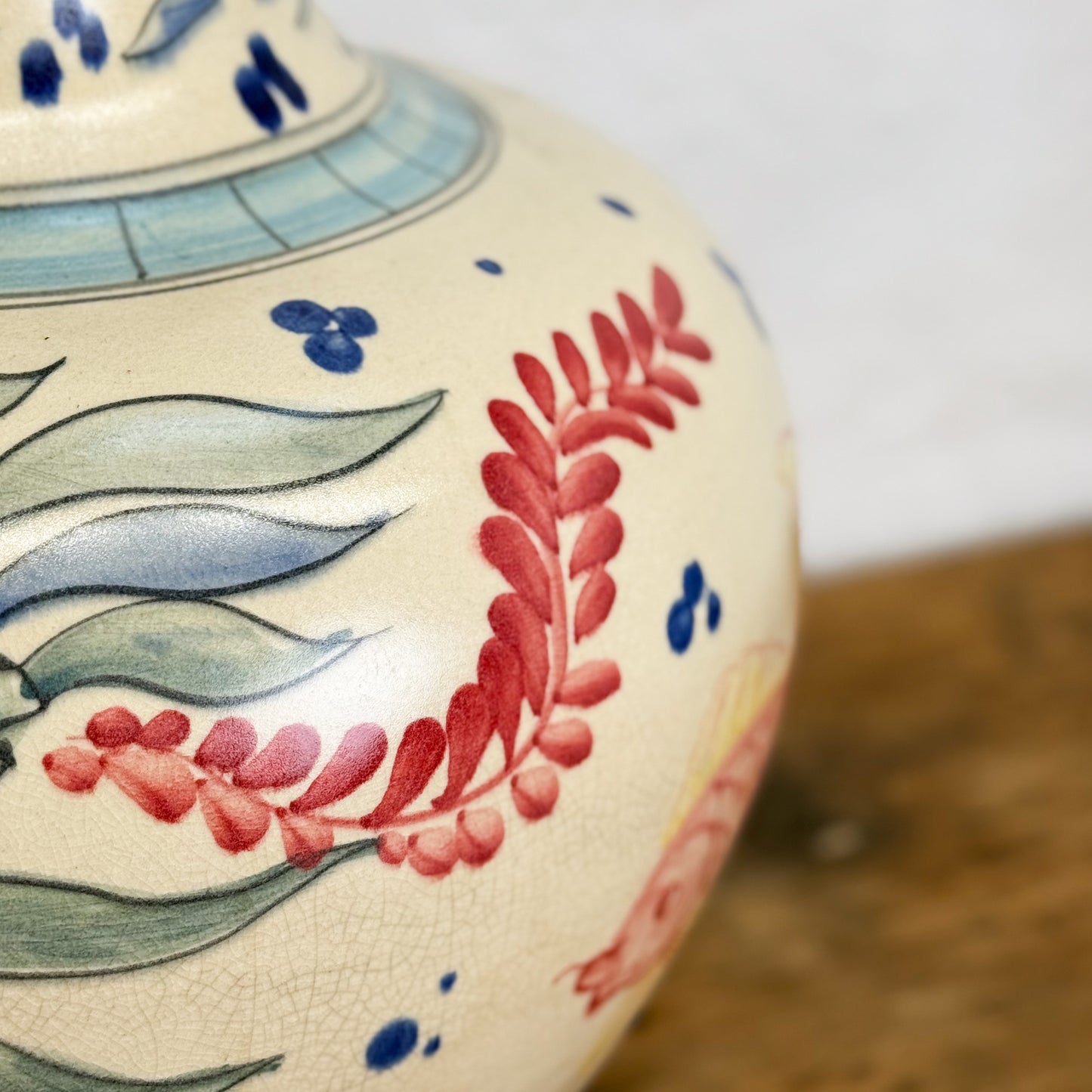 Close-up of a ceramic vase with floral designs on a wooden surface.