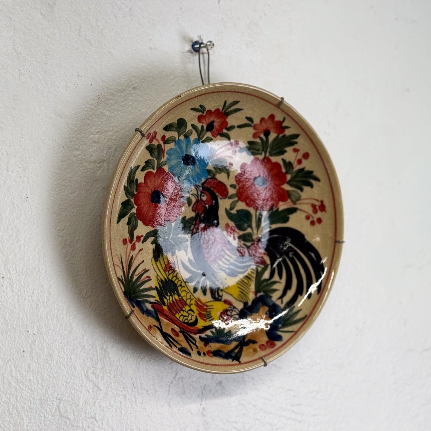 Decorative plate with rooster design on a white wall